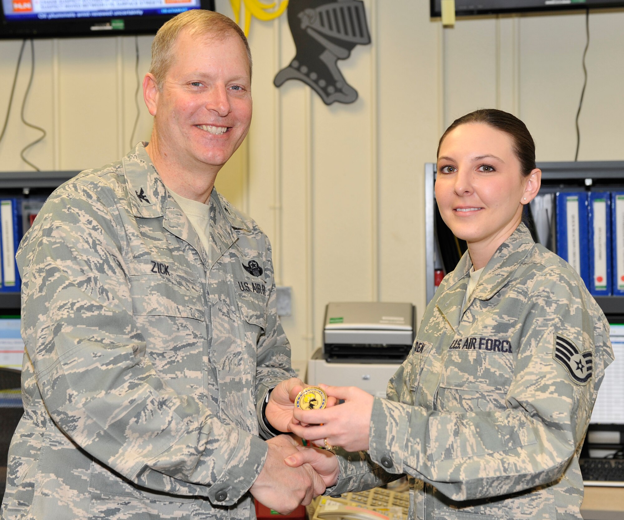 Col. Michael Zick, 19th Airlift Wing vice commander, presents a coin to Staff Sgt. Karlie Madden, 19th Airlift Wing Command Post NCO-in-charge of training, March 16 at Bldg. 160 for her selection as the Combat Airlifter of the Week. Sergeant Madden tailored the unit training plan with zero errors. Her training program was benchmarked by Air Mobility Command and is in use by 11 AMC Command Posts and one Pacific Air Force Command Post. (U.S. Air Force photo by Senior Airman Christine Clark)