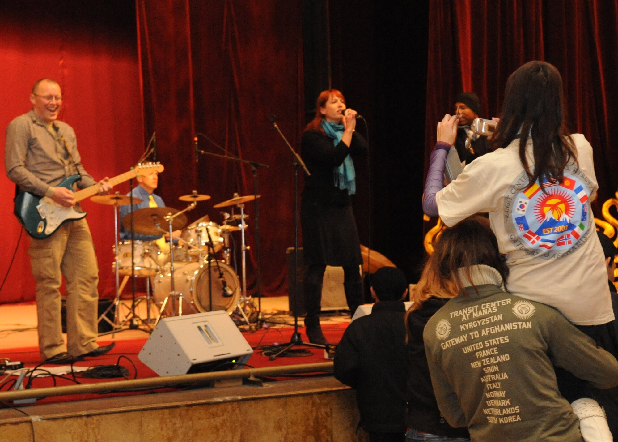 Audience members take pictures during a performance by the U.S. Air Forces Central Public Affairs band ?Reserve Generation? at the House of Culture in Tokmok, Kyrgyzstan, March 12, 2010. Reserve Generation had the unique opportunity to play for the local community during their 60-day tour through Southwest Asia. (U.S. Air Force photo/Senior Airman Nichelle Anderson/released)