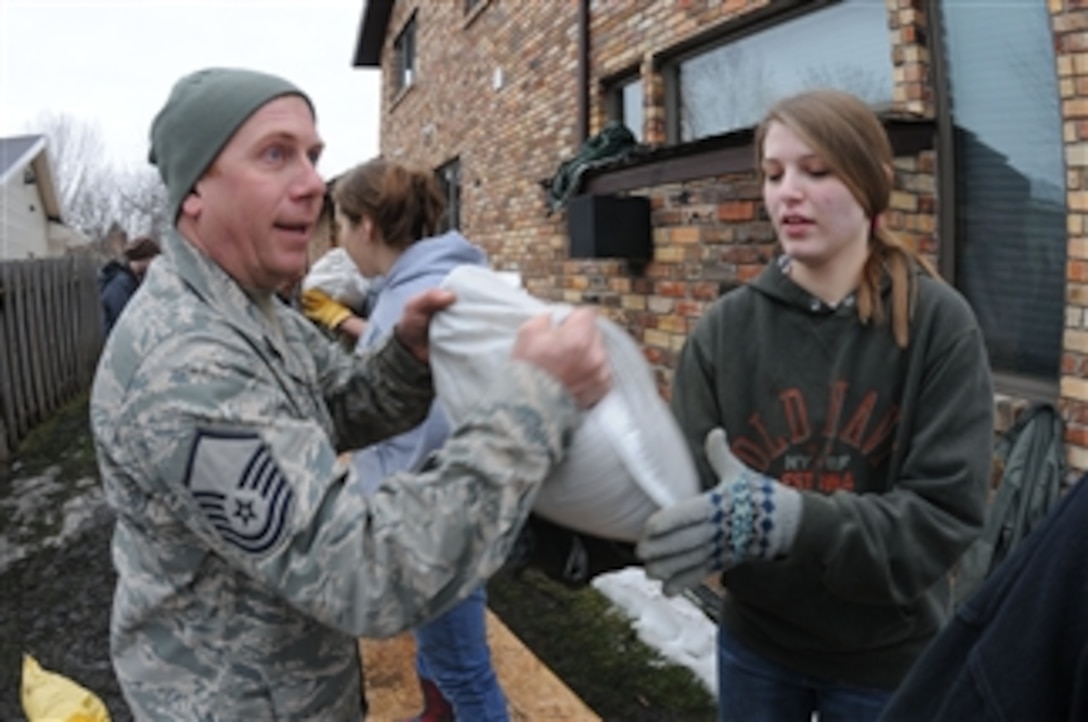 U.S. Air Force Master Sgt. Jody Saatoff, with the 119th Civil Engineer Squadron, hands a sandbag to a civilian volunteer in Fargo, N.D., on March 16, 2010.  Airmen with the 119th Wing joined volunteers to prevent the rising Red River from flooding areas of the city.  