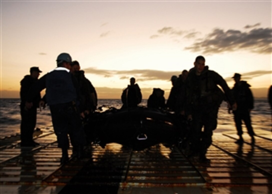 U.S. Navy sailors from the dock landing ship USS Harpers Ferry (LSD 49) and Marines from Fox Company, 2nd Battalion, 7th Marine Regiment, 31st Marine Expeditionary Unit carry a combat rubber raiding craft aboard the ship in Luzon, Philippines, on March 15, 2010.  
