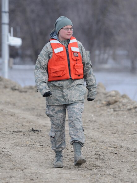 Staff Sgt. Elise Peterson, of the 119th Maintenance Squadron, monitors an earthen food dike March 18, Fargo, N.D.  Peterson is walking the dike in an effort to keep people from walking on the flood barrier and to monitor it for problem areas to catch them and report them before they can become too large to contain. 