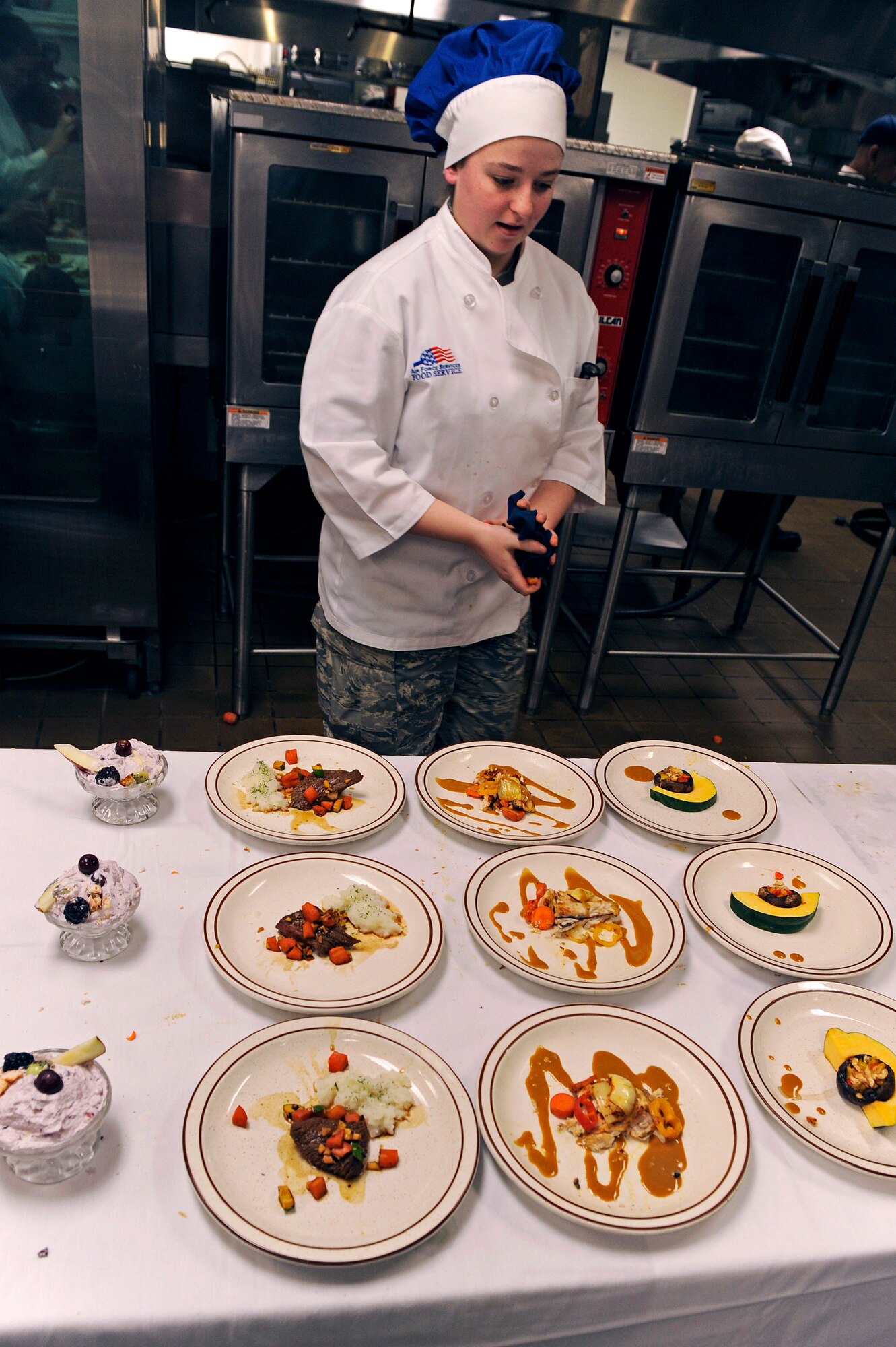 ELLSWORTH AIR FORCE BASE, S.D. -- Airman 1st Class Steffanie Whipple, 28th Force Support Squadron food services technician, does a final inspection of the dishes she and her team created during the second annual Ellsworth Iron Chef competition, March 17.  Their dishes consisted of stuffed mushrooms, Cajun fish, teriyaki steak and whipped fruit. (U.S. Air Force photo/Senior Airman Marc I. Lane)