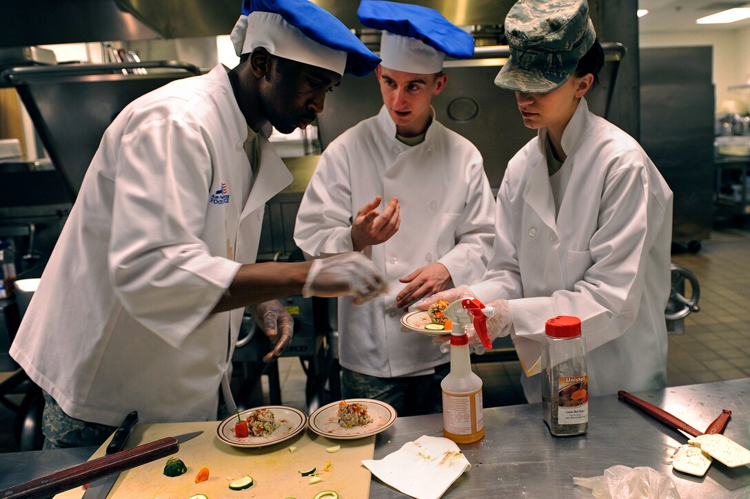 ELLSWORTH AIR FORCE BASE, S.D. -- (From left) Airman 1st Class Desmond Boone, Airman Anthony Bruhl and  Airman 1st Class Ashleigh Morford, 28th Force Support Squadron food services technicians, prepare a milk-fish entrée during the second annual Ellsworth Iron Chef competition, March 17.  The teams had one hour to prepare three dishes using corned beef, milk-fish, cabbage, peppers, mushrooms, fruits, parsnips, turnips and onions into an appetizer, entrée and dessert. (U.S. Air Force photo/Senior Airman Marc I. Lane)