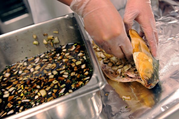 ELLSWORTH AIR FORCE BASE, S.D. -- Senior Airman Ross Conchas, 28th Force Support Squadron food services technician, prepares a milkfish with a vinegar-based onion sauce during the second annual "Ellsworth Iron Chef" competition, March 17. The competition had an Irish theme in the spirit of St. Patrick's Day. Each dish, including the dessert, had to contain either milk-fish or corned beef. (U.S. Air Force photo/Senior Airman Marc I. Lane)