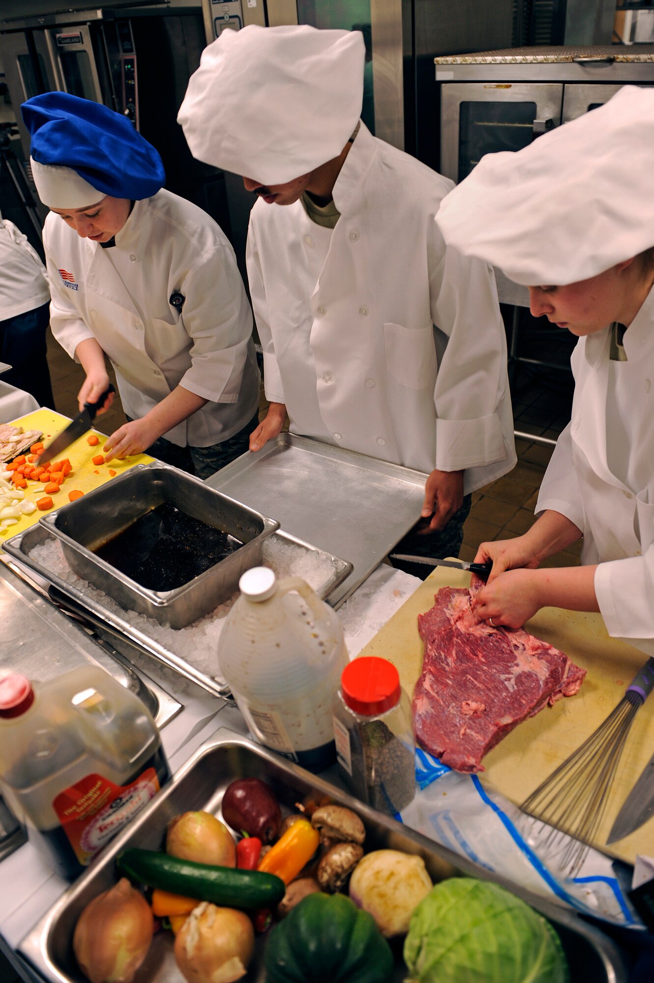 ELLSWORTH AIR FORCE BASE, S.D. -- (From left) Airmen 1st Class Steffanie Whipple, Michael Azares and Sarah Meador, 28th Force Support Squadron food services technicians, prepare a teriyaki corned beef for the second annual Ellsworth Iron Chef competition, March 17.  Their dishes consisted of stuffed mushrooms, Cajun fish, teriyaki steak and whipped fruit. (U.S. Air Force photo/Senior Airman Marc I. Lane)