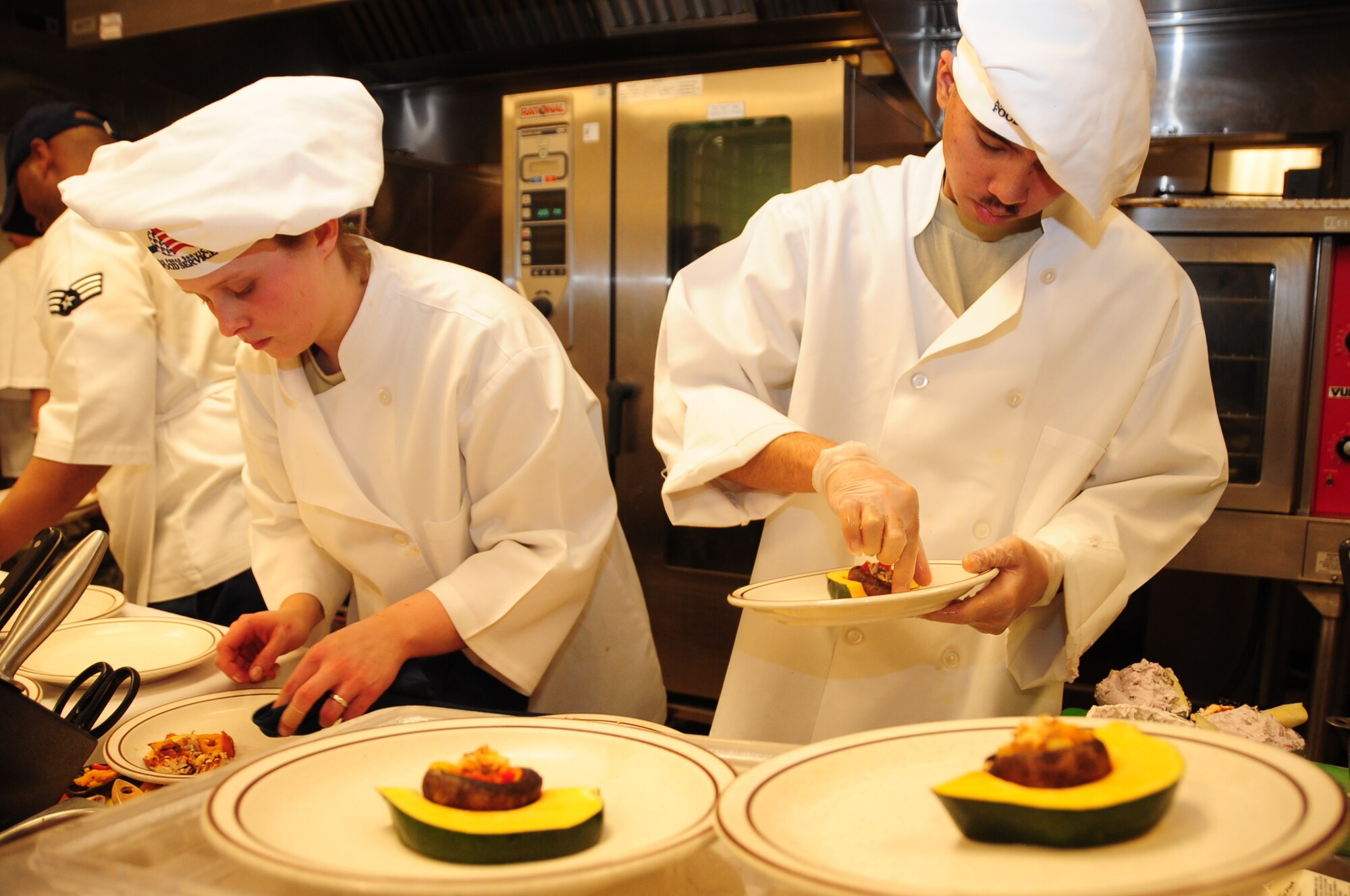 ELLSWORTH AIR FORCE BASE, S.D. -- (Left to right) Airmen 1st Class Sarah Meador and Michael Azares, 28th Force Support Squadron cooks, put the final touches on their appetizers during the Ellsworth Iron Chef competition, March 17.   The competition consisted of four teams competing against each other to complete three dishes in one hour. (U.S. Air Force photo/Airman 1st Class Anthony Sanchelli)

