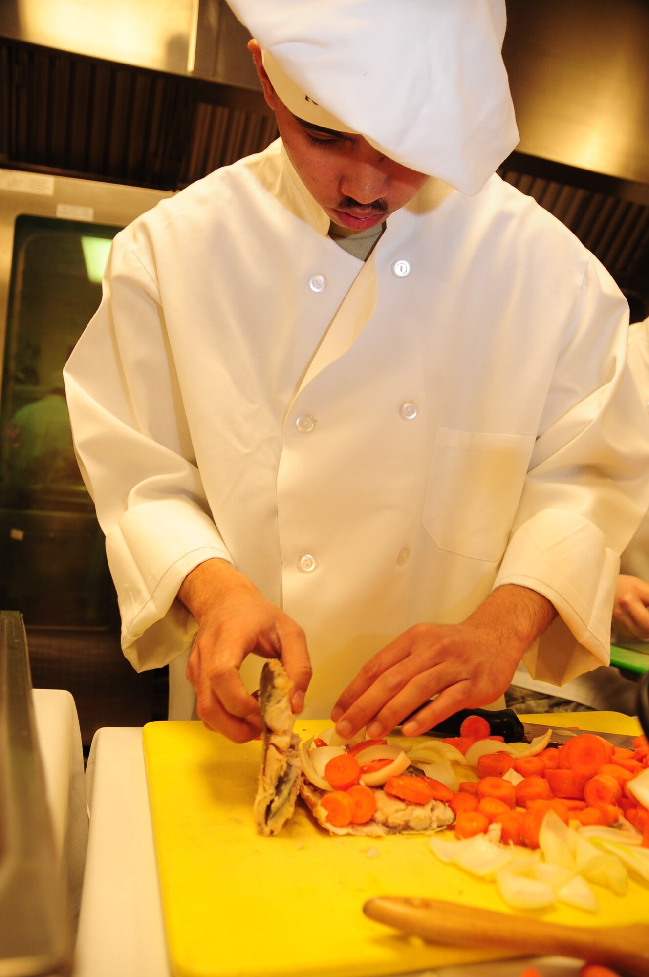 ELLSWORTH AIR FORCE BASE, S.D. -- Airman 1st Class Michael Azares, 28th Force Support Squadron cook, stuffs a fillet milk fish with an assortment of vegetables and spices during the Ellsworth Iron Chef competition, March 17.   The hour-long competition  pitted  four teams  against each other and challenged participants to create three dishes utilizing a “secret ingredient,” either milk fish or corned beef. (U.S. Air Force photo/Airman 1st Class Anthony Sanchelli)
