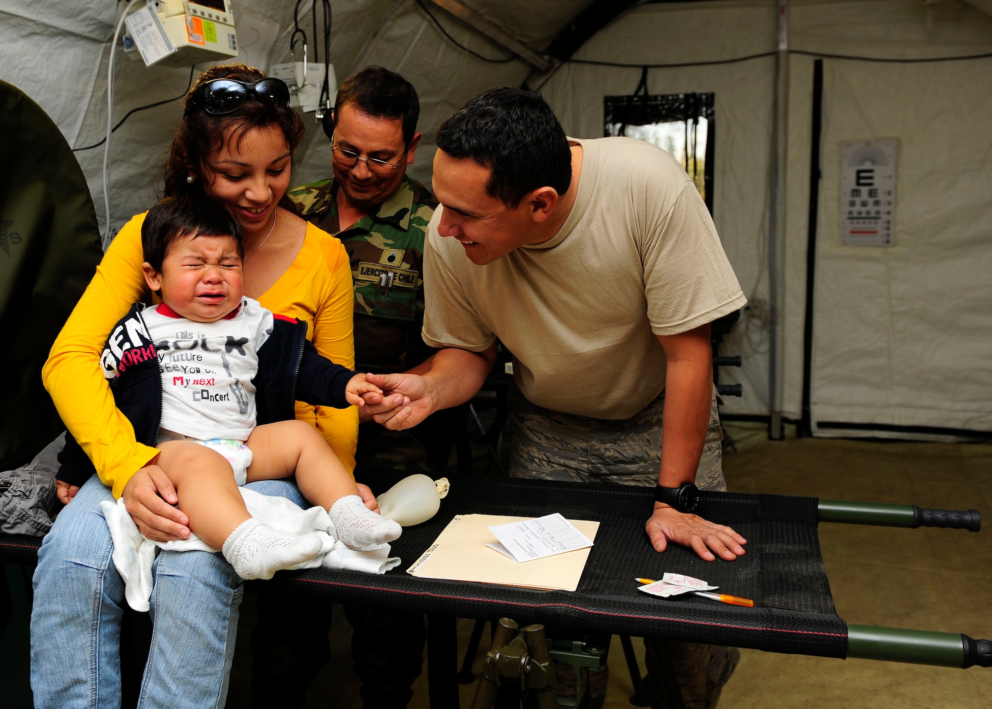 Staff Sgt. Abraham Rodriguez (right) comforts a crying Chilean child at the expeditionary hospital March 14, 2010, in Angol, Chile. Sergeant Rodriguez is a translator for more than 80 members of the Air Force Expeditionary Medical Support Team here. Sergeant Rodriguez is the NCO in charge of Defense Institute for Medical Operations at the Air Force School of Aerospace Medicine at Brooks City-Base, Texas. (U.S. Air Force photo/Senior Airman Tiffany Trojca)