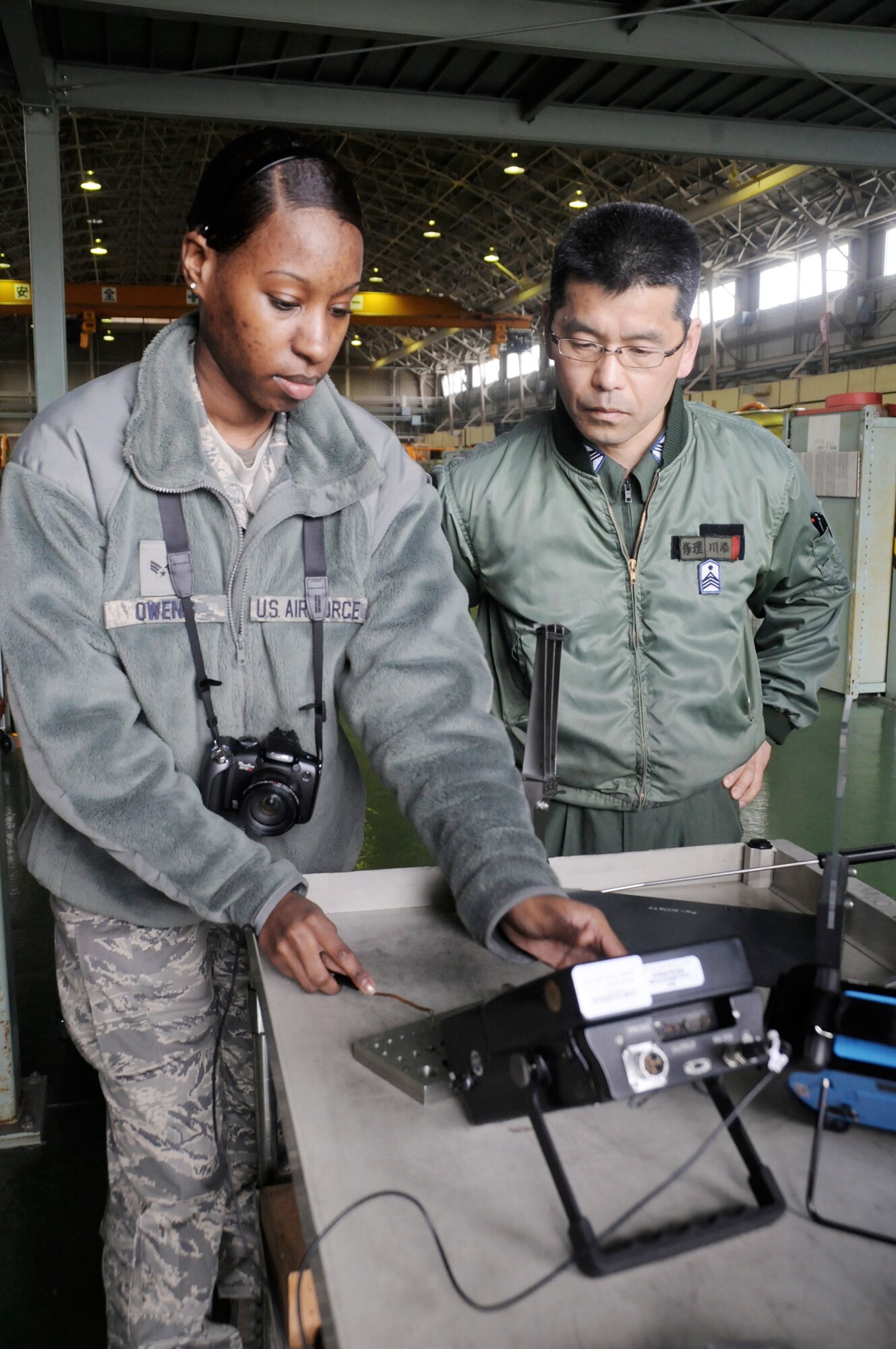 Senior Airman Danielle Owens compares the equipment she uses to check for engine cracks to the equipment of Japan Air Self Defense Force Master Chief Sgt. Kawasoe during an aviation training relocation exercise March 8, 2010, Tsuiki Air Base, Japan. Airman Danielle is a 35th Maintenance Squadron non-destructive inspections specialist. (U.S. Air Force photo/Staff Sgt. Rachel Martinez)

