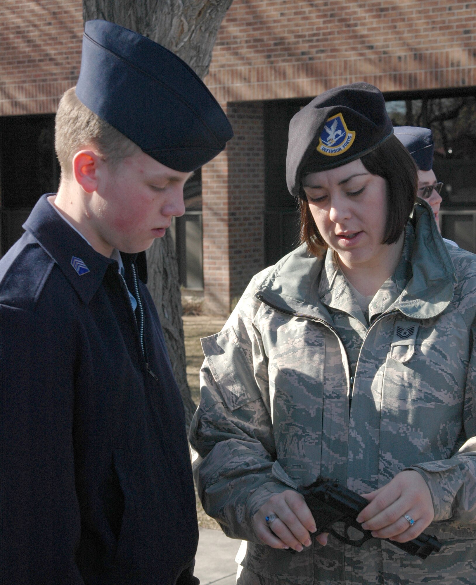 Tech. Sgt. Crystal Lovato, a member of the Air Force Reserve's 302nd Security Forces Squadron, shows AF Junior Reserve Officer Training Corps Cadet James La Valle a 9mm pistol March 17 at Peterson Air Force Base, Colo. The JROTC member, together with more than 150 other cadets from around Colorado, toured Peterson and the AF Reserve's 302nd Airlift Wing, where they learned about unique jobs and opportunities with the AF Reserve. (U.S. Air Force photo/Tech. Sgt. Daniel Butterfield)
