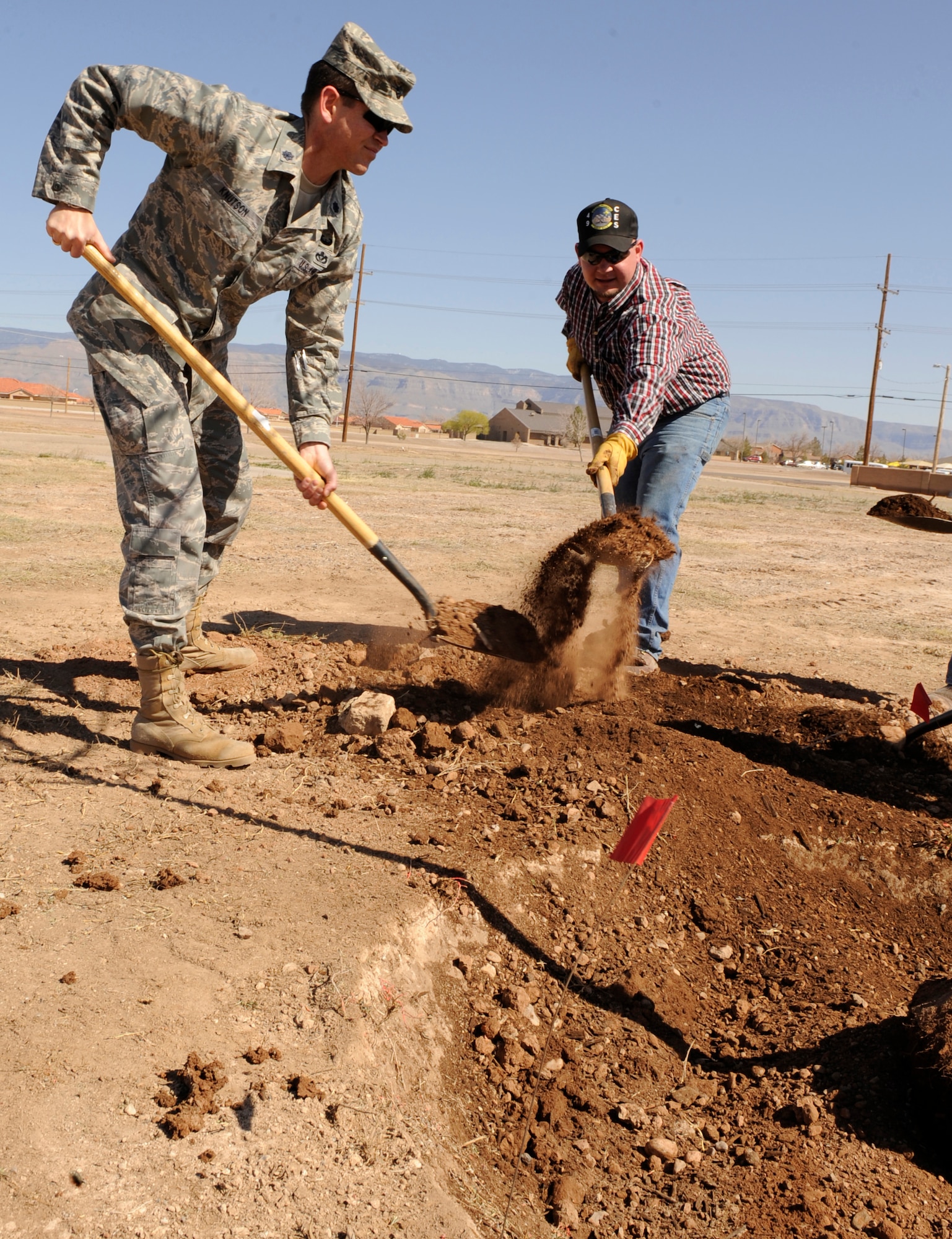 HOLLOMAN AIR FORCE BASE, N.M. -- Lt. Col. Christian Knutson, 49th Civil Engineer Squadron commander, helps Lucas Oligschlaeger, Base natural resource biologist, put the finishing touches on the Arbor Day tree across the street from the officer's club March 12, 2010 to commemorate the annually celebrated Arbor Day.  Holloman was awarded Tree City USA status by the Arbor Day Foundation and has been a part of the celebration for the past six years.  (U.S. Air Force photo by Airman 1st Class Eileen Payne)