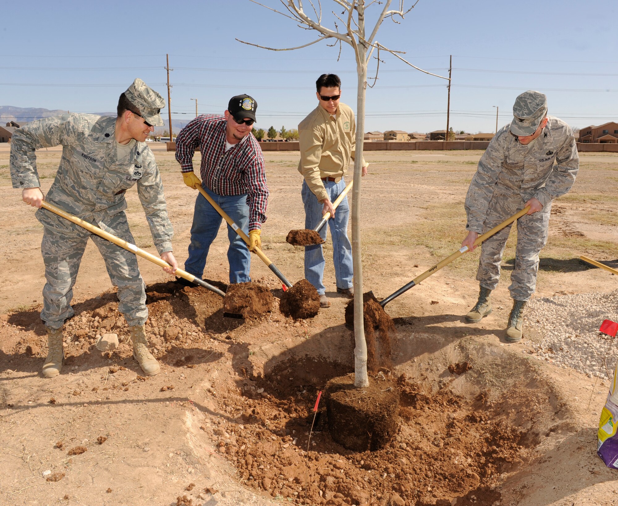 HOLLOMAN AIR FORCE BASE, N.M. -- Lt. Col. Christian Knutson, 49th Civil Engineer Squadron commander; Col.  Stephen DiFonzo, 49th Mission Support Group commander; Lucas Oligschlaeger,base natural resource biologist; and Andrew Frederick, New Mexico State Forestry timber management officer, help plant a tree for the annual Arbor Day event across the street from the officer's club March 12, 2010. Holloman was awarded Tree City USA status by the Arbor Day Foundation and has been a part of the celebration of Arbor Day for the past six years. (U.S. Air Force photo by Airman 1st Class Eileen Payne)