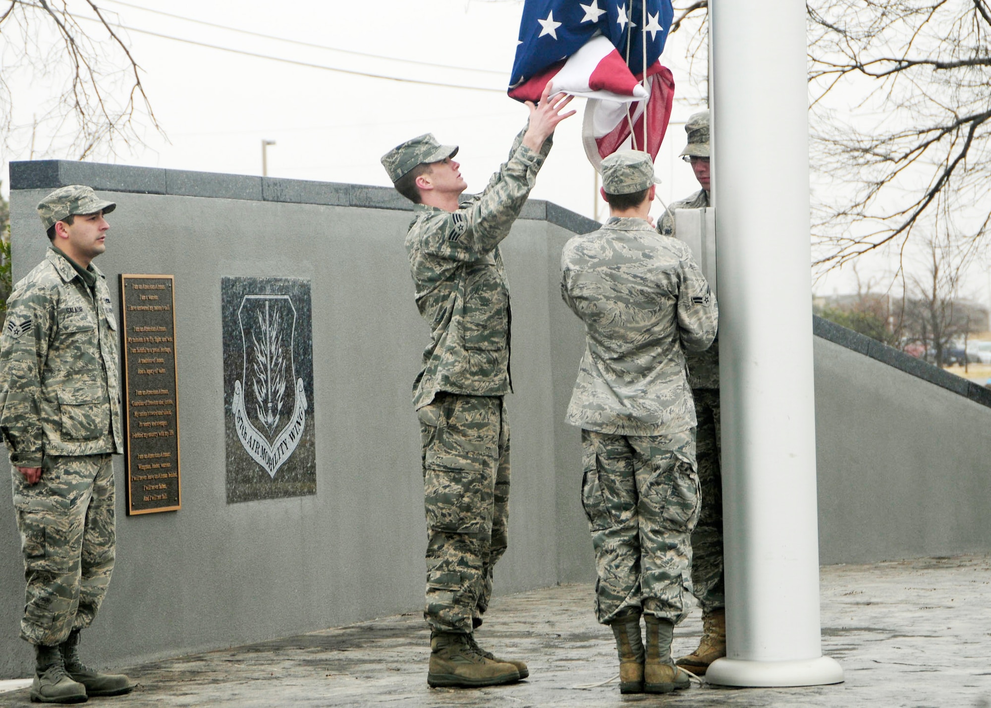 (From left) Senior Airmen Raymond Salazar and Ryan Gava and Airmen 1st Class Chris Schaaf and Thomas Baszler raise the flag at the Wings of Freedom Park on Feb. 3, 2010, following an ice storm at Altus Air Force Base, Okla. (U.S Air Force photo/Airman 1st Class Myles T. Stepp)