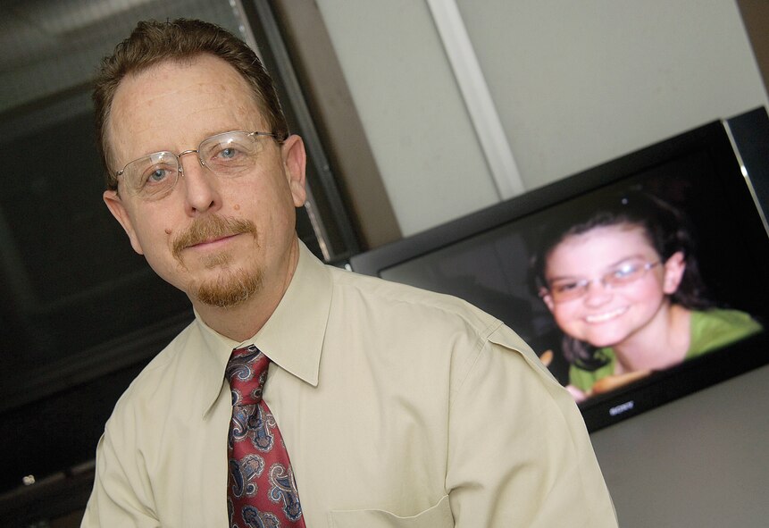 Brion Ockenfels, 72nd Air Base Wing Public Affairs specialist, is pictured with a photo of Lauren-Ashley Morton, the young girl he donated bone marrow to in 2005. Mr. Ockenfels said Lauren-Ashley was his 'special forces girl.' (U.S. Air Force photo/Margo Wright) 