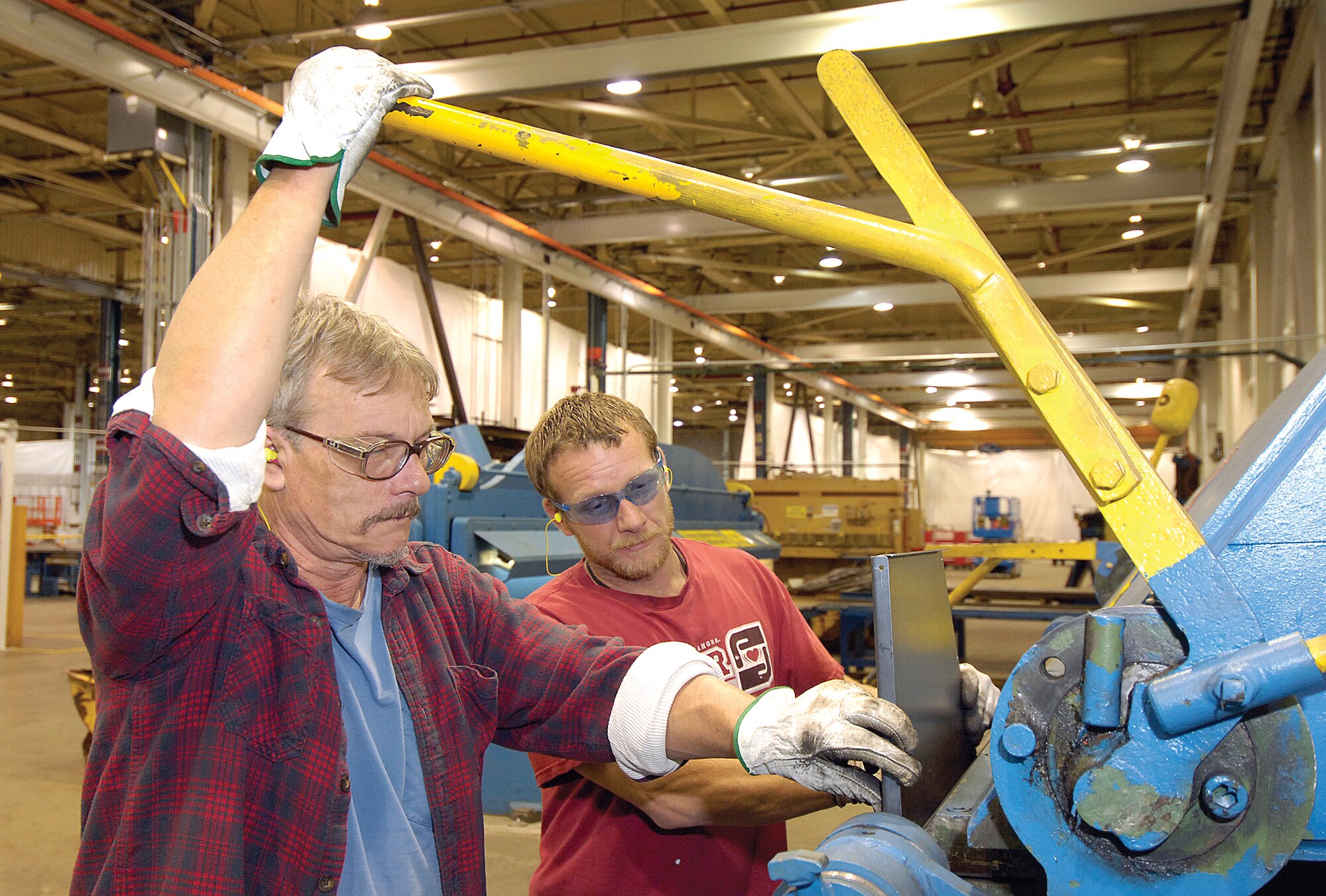 In the 76th Maintenance Squadron’s sheet metal and welding shop now in Bldg. 9001, Steve Horton, front and Eddie Jones bend steel to make a shop aid.  Squadron members have been an integral part of taking a dark and deserted GM plant and turning it into a clean, new facility for Tinker maintenance shops. Pipe fitters, electricians, welders and other tradesmen are scattered throughout the building demolishing old structures and building new shops. (Air Forc photo by Margo Wright)
