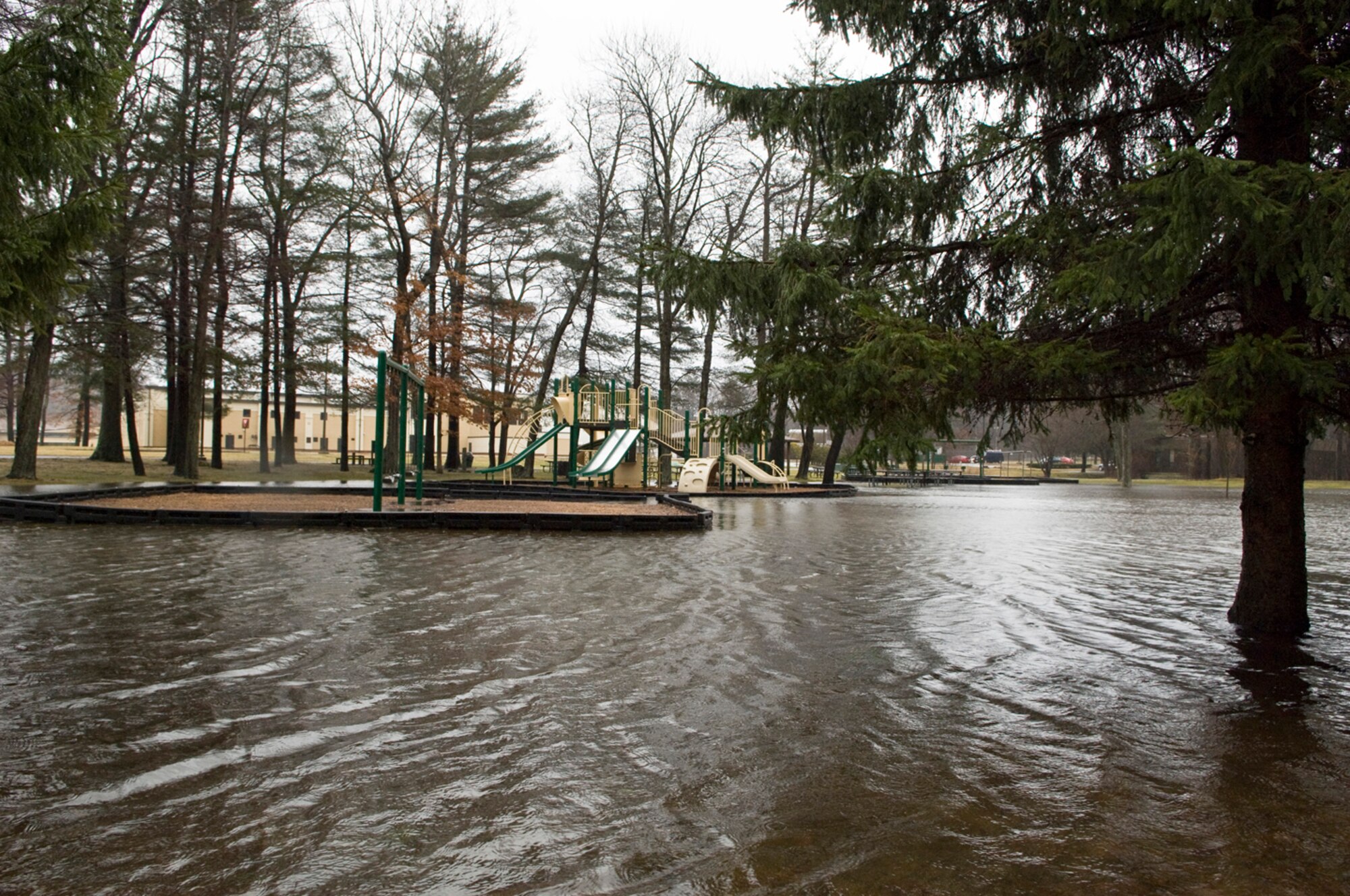 Thousands were impacted by the recent heavy rains that blanketed the New England area for three days.  Several locations around the base were closed due to the severe flooding.  Here waters flood out the playground area adjacent to the Youth Center.   With sunshine and warmer temperatures predicted for the next few days the waters in and around Hanscom are expected to recede allowing for cleanup efforts to safely begin. (U.S. Air Force photo by Mark Herlihy)