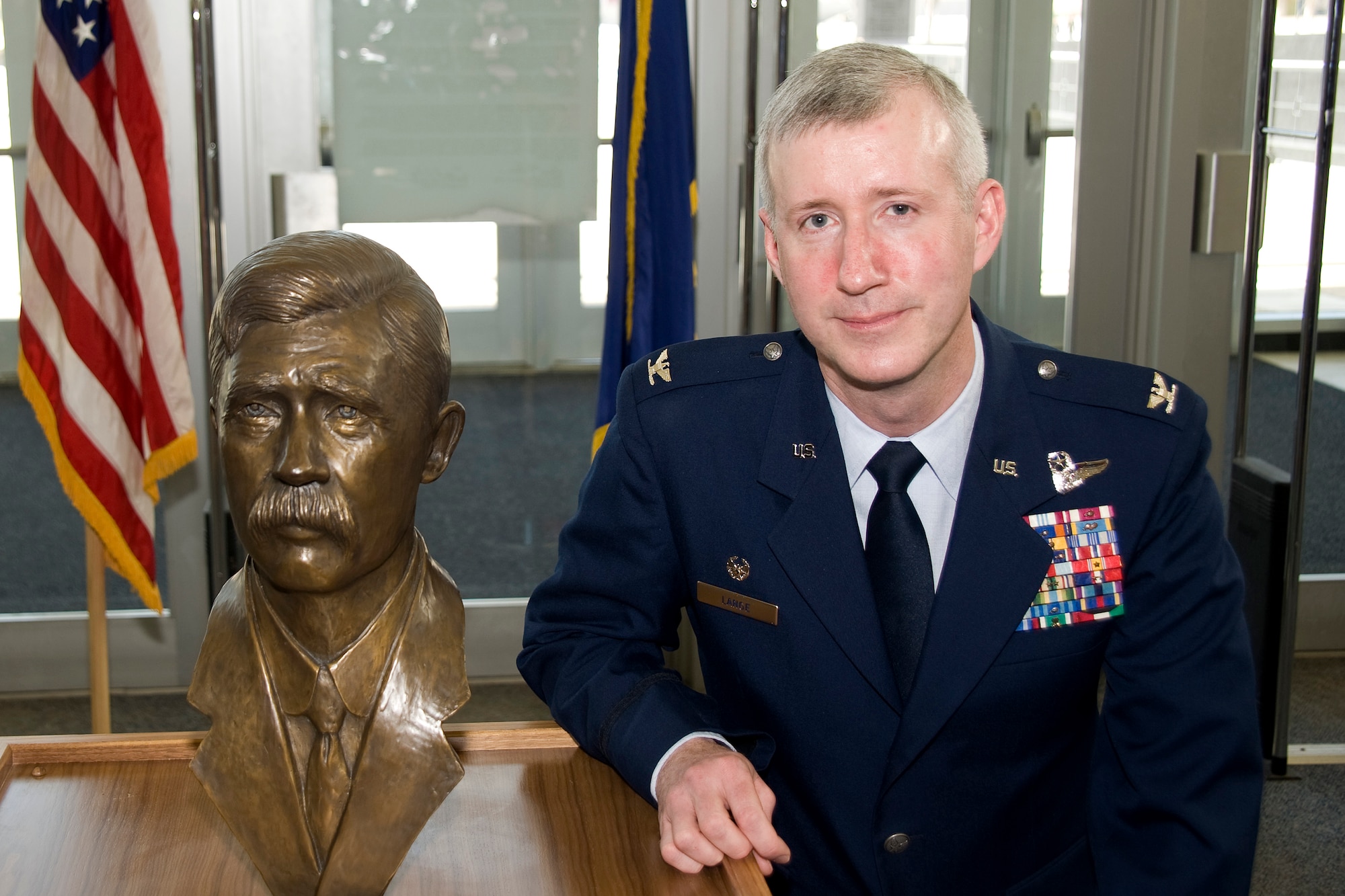Col. David Lange poses next to a bust of his great, great uncle, Charlie Taylor, in the Air Force Academy's McDermott Library March 2, 2010. Mr. Taylor built the first aircraft engine used by the Wright Brothers and helped the brothers prepare the "Military Flyer" for demonstration to the U.S. Army at Fort Myer, Va. Colonel Lange is the air officer commanding for Cadet Group 2. (U.S. Air Force photo/Bill Evans)
