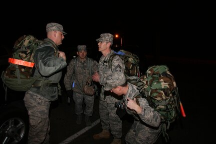 ROBINS AIR FORCE BASE, Ga. - Lt. Col. Todd Schug, 52nd Combat Communications Squadron and ruck march commander, (left) and Staff Sgt. Rome Reiswig, 52nd CBCS Customer Support Squadron non-commissioned officer in charge, talk with Chief Master Sgt. Shawn Coyle, 52nd CBCS superintendent, about the ruck march route while 2nd Lt. Patrick Beville prepares his ruck pack. The route would take more than 30 members of the 689th Combat Communications Wing across six miles of Robins’ roadways and woodlands March 15, in honor of Chief Coyle’s retirement March 19. (U.S. Air Force Photo/2nd Lt. Joel Cooke)