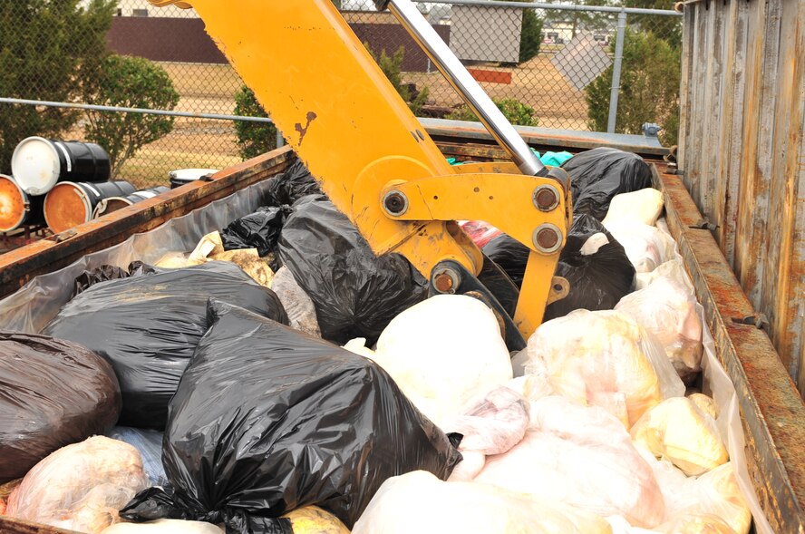 A heavy equipment operator uses a back-hoe to compress bundles of absorbents contaminated with used oil in a roll-off waste container located on Seymour Johnson Air Force Base, N.C., March 12, 2010. Base personnel use absorbents to clean weapons and minor spills of hydraulic fluid, oil and fuel. (U.S. Air Force photo/Senior Airman Rae Perry)