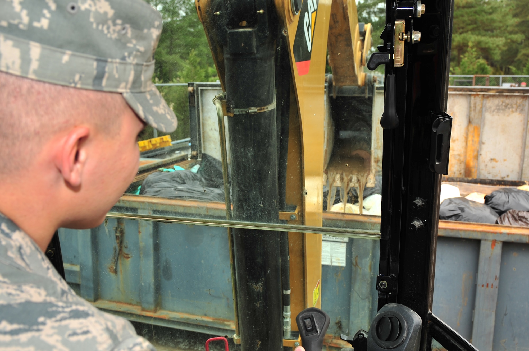 Airman Elliot Westerman, 4th Civil Engineer Squadron heavy equipment operator, uses a backhoe to compress absorbents contaminated with used oil at Seymour Johnson Air Force Base, N.C., March 12, 2010. After Central Accumulation Site personnel receive a delivery of JP-8 absorbents, a technician processes them in a centrifuge to remove liquids before disposal. Westerman hails from Boswell, Pa. (U.S. Air Force photo/Senior Airman Rae Perry)