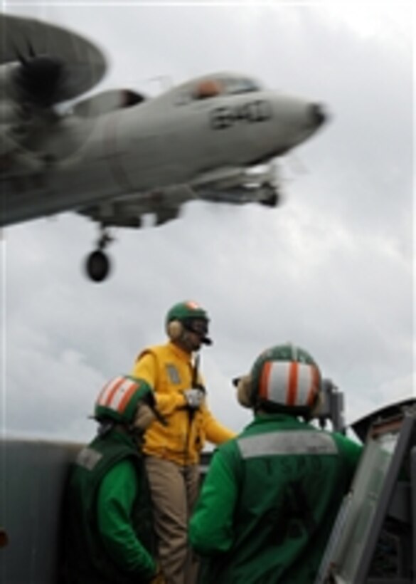 U.S. Navy air department sailors ensure the safety of the flight deck as an E-2C Hawkeye aircraft assigned to Carrier Airborne Early Warning Squadron 120 lands aboard the aircraft carrier USS George H.W. Bush (CVN 77) underway in the Atlantic Ocean on March 12, 2010.  The ship is operating in support of fleet training operations.  