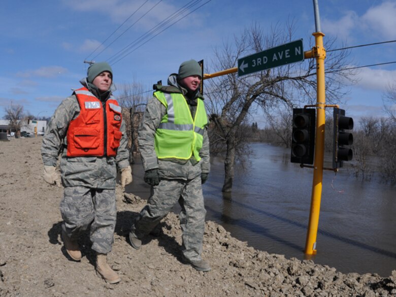 Senior Airman Jeremiah Colbert, of the 119th Maintenance Squadron, left, and Staff Sgt. Joshua Hahn, of the 119th Logistics Readiness Squadron, patrol a flood dike March 19 along the Red River in downtown Fargo, N.D. The pair of North Dakota Air National Guard members are tasked with keeping sightseers off of the flood dikes and also to monitor the clay dikes for possible trouble spots that could become breaches in the dike if they are left unchecked. (DoD photo by Senior Master Sgt. David H. Lipp) (Released)