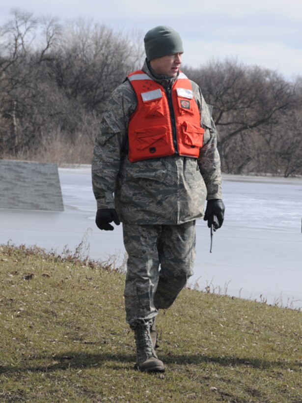 Staff Sgt. James Pollard, of the 119th Logistics Readiness Squadron, patrols a flood dike March 19 along the Red River in Fargo, N.D. The North Dakota Air National Guard member was tasked with keeping sightseers off of the flood dikes and also monitoring the clay dikes for possible trouble spots that could become breaches in the dike if they are left unchecked. The roof of a submerged garage can be seen in the water behind Pollard as we walks at the waters’ edge.    (DoD photo by Senior Master Sgt. David H. Lipp) (Released)