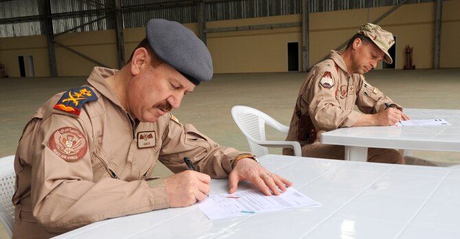 Staff Lt. Gen. Anwer Ameen, Iraqi air force commander, and Brig. Gen. Scott Hanson, 321st Air Expeditionary Wing commander, and sign a letter of acceptance and transfer March 10, 2010, for the newly restored Skeleton Hangar on Kirkuk Regional Air Base, Iraq. Members of the Iraq Training and Advisory Mission-U.S. Air Force and the Iraqi air force participated in the ceremony. (U.S. Air Force photo/Staff Sgt. Tabitha Kuykendall)