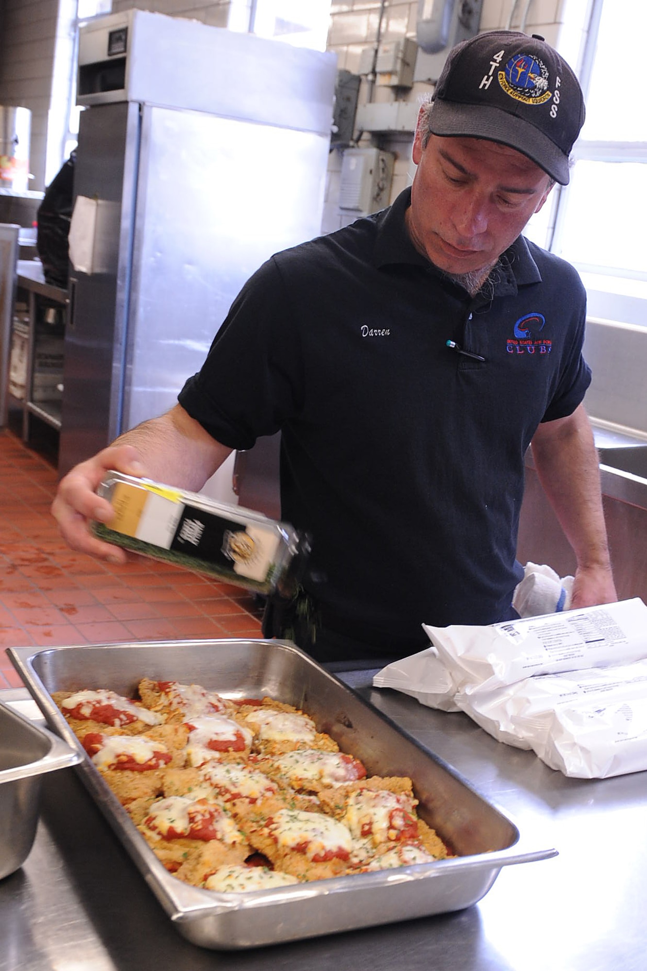 Darren Dias, Simply Seymour's Too cook, shakes parsley flakes over chicken parmesan on Seymour Johnson Air Force Base N.C., March 18, 2010. Parsley is a green herb used for flavoring and visual appeal. Dias is from Boston. (U.S. Air Force photo/ Senior Airman Whitney Lambert)