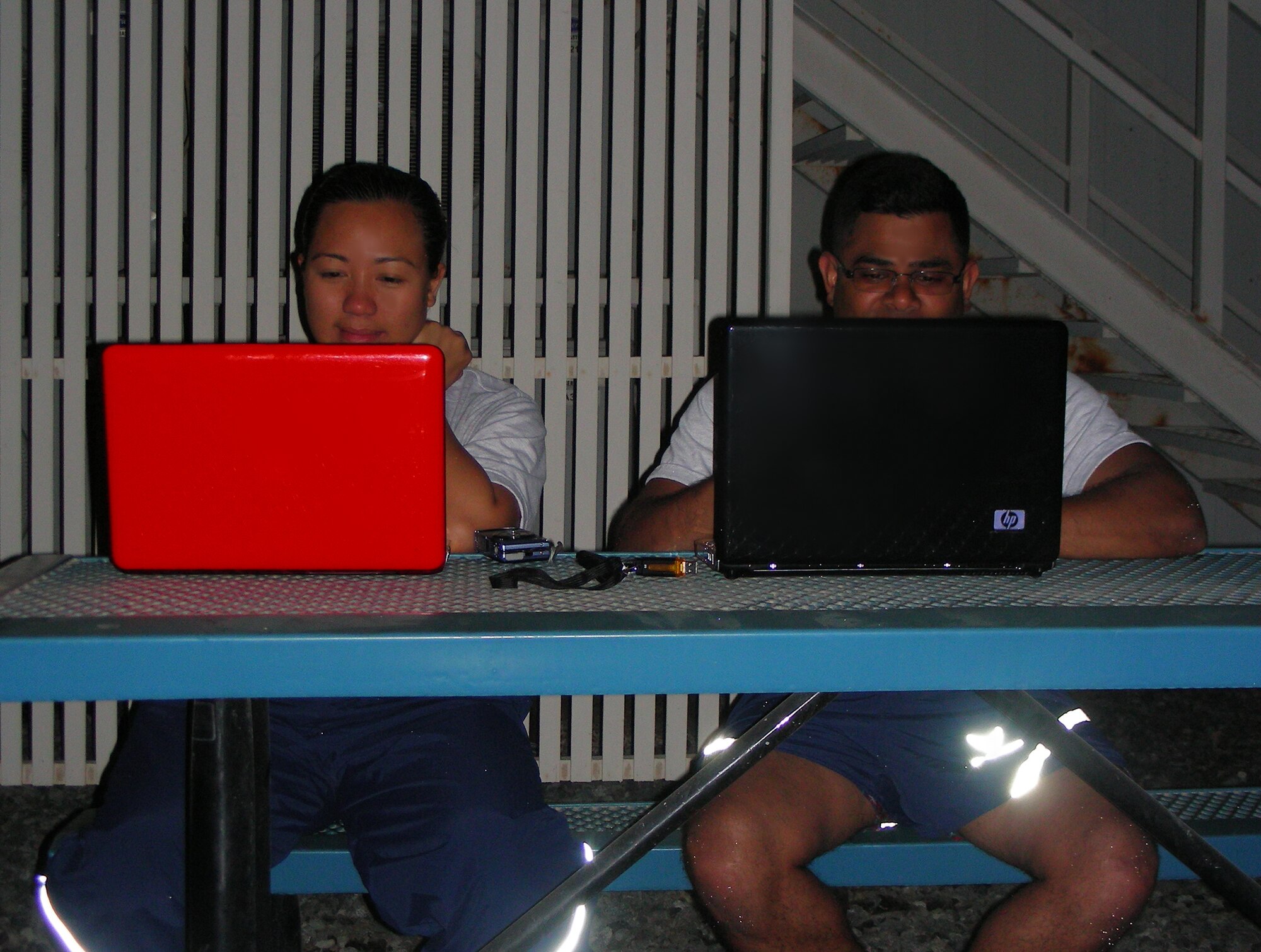 Tech. Sgt. Aliza Adanza (left) and Staff Sgt. Gautambhai Patel, both of the 380th Expeditionary Logistics Readiness Squadron, at an undisclosed base in Southwest Asia, use their laptops March 18 outdoors to connect with their friends families back home using wireless internet connections. Recently wireless was enabled inside the dormitories of all 1900 service members who live and work at the 380th Air Expeditionary Wing. Being able to stay in touch with loved ones boosts the morale of deployed personnel. (U.S. Air Force Photo/Capt. Cathleen Snow/Released)