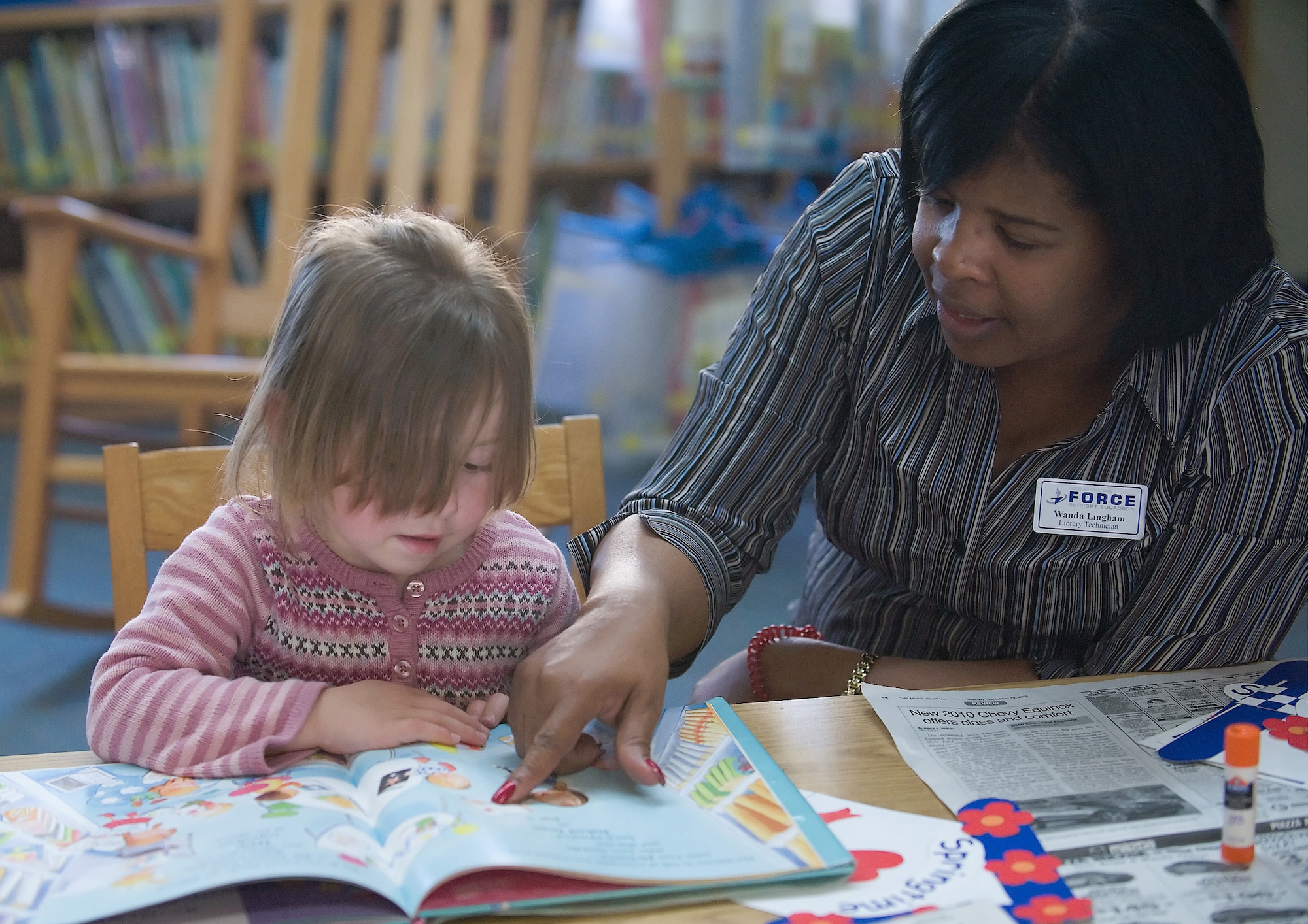 (Left to Right) Katie Jordan, four-year-old daughter of Staff Sgt. Meghann Roper, 436th Logistics Readiness Squadron, and Staff Sgt. Justin Roper, 736th Aircraft Maintenance Squadron, listens as Wanda Lingham, 436th Force Support Squadron library technician and storyteller, reads a book during Library Story Time, a weekly event offered Wednesdays from 10:30 ? 11:30 a.m. (U.S. Air Force photo/ Brianne Zimny)