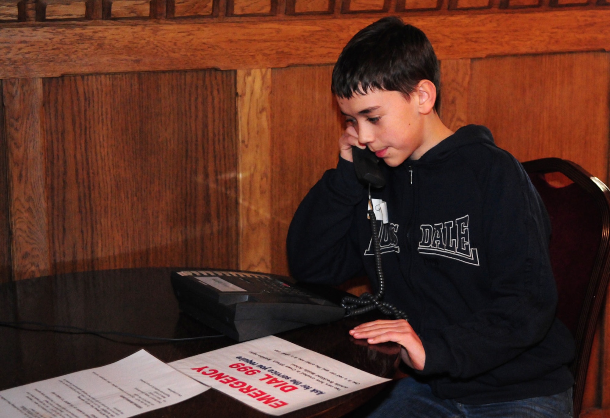 Grant DeJesus, 11, a student at Liberty Intermediate School, practices making an emergency '999' call at the Crucial Crew event March 10 at Mildenhall Stadium. The annual event, organized by Forest Heath crime prevention panel, was for British and American school children from local middle schools. The American children were taught the difference between a '911' call (on base only) and a '999' (off base) emergency call.  (U.S. Air Force photo/Karen Abeyasekere)