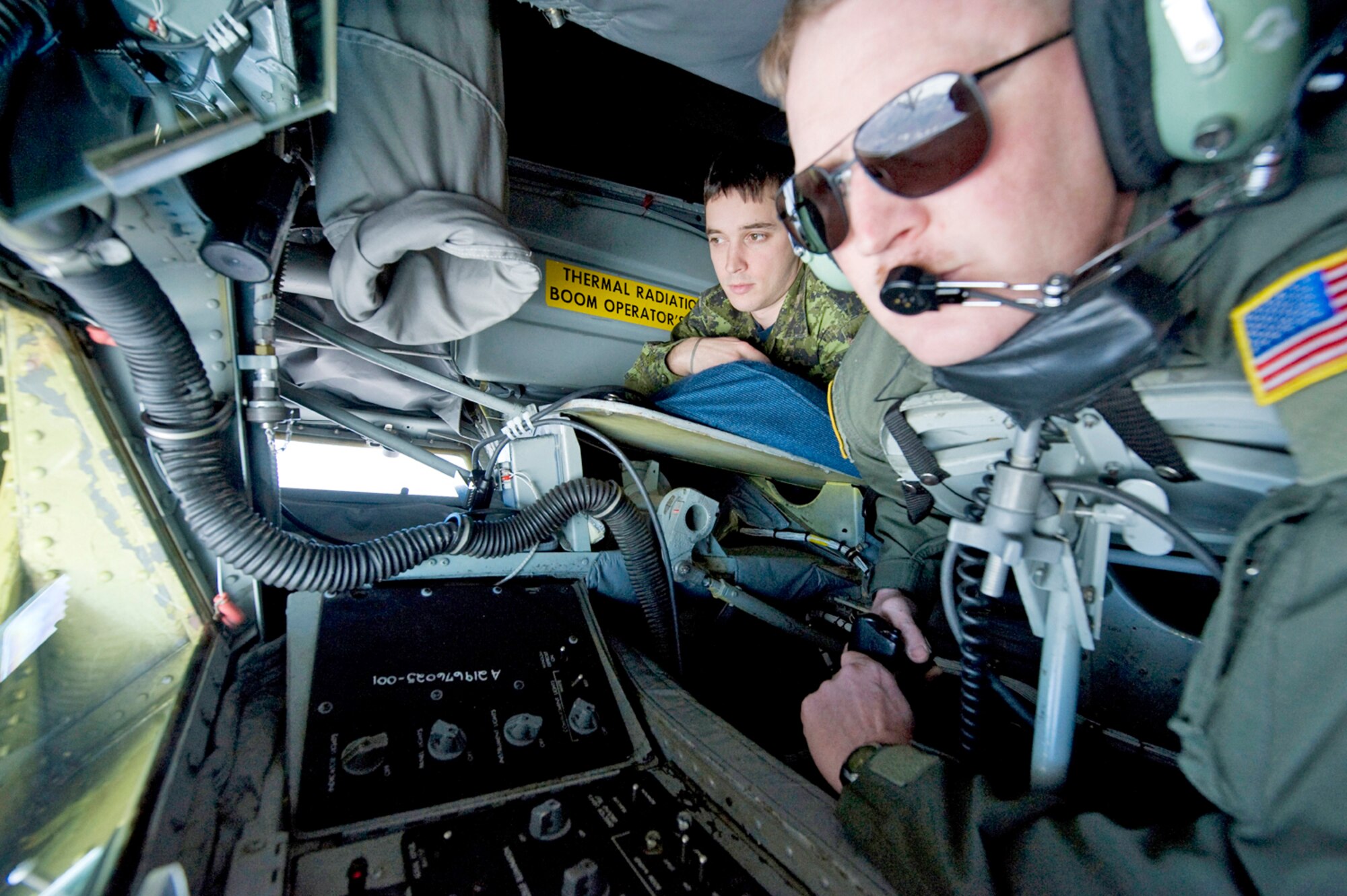 Master Sgt. Brian Quam prepares the boom on a KC-135 Stratotanker to refuel a C-17 Globemaster as Canadian Capt. Eric Rheaume (background) observes during an orientation flight March 17, 2010,  at Altus Air Force Base, Okla. Captain Rheaume is a maintenance officer with the Canadian air force's 425th Tactical Fighter Squadron and Sergeant Quam is the NCO in charge of training for the 54th Air Refueling Squadron. (U.S. Air Force photo/Master Sgt Jack Braden)