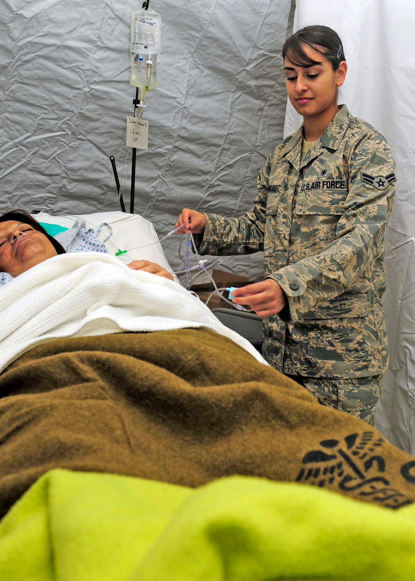 Airman 1st Class Yadira Fernandez adjusts a patient's intravenous line at an expeditionary hospital March 17, 2010, in Angol, Chile. Airman Fernandez is an aerospace medical technician also working as a translator for the Air Force Expeditionary Medical Support team here. She is deployed from the 59th Medical Inpatient Squadron at Lackland Air Force Base, Texas. (U.S. Air Force photo/Senior Airman Tiffany Trojca)
