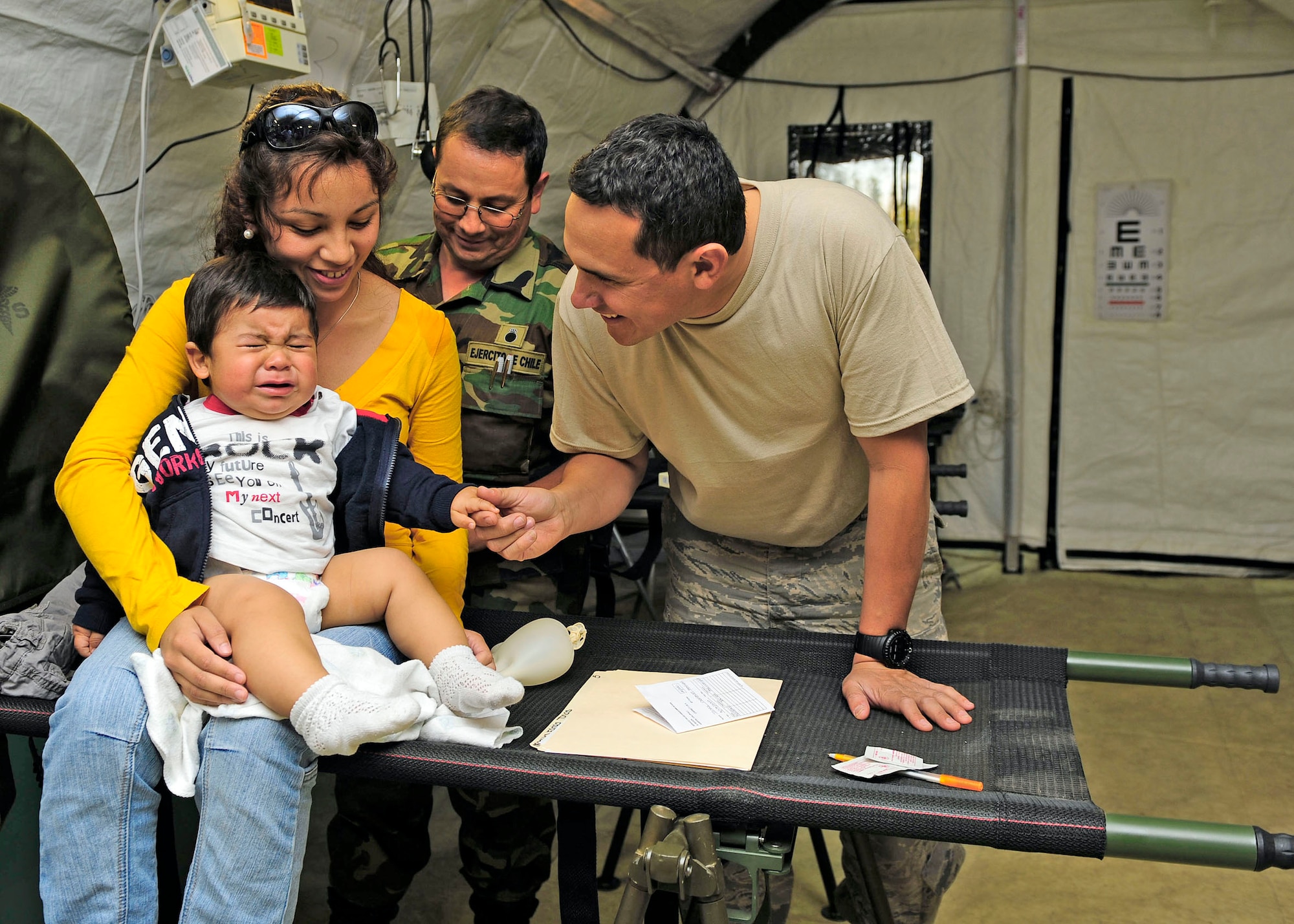 Staff Sgt. Abraham Rodriguez (left) comforts a crying Chilean child at the expeditionary hospital March 14, 2010, in Angol, Chile. Sergeant Rodriguez is a translator for more than 80 members of the Air Force Expeditionary Medical Support Team here. Sergeant Rodriguez is the NCO in charge of the Defense Institute for Medical Operations at the Air Force School of Aerospace Medicine at Brooks City-Base, Texas. (U.S. Air Force photo/Senior Airman Tiffany Trojca)
