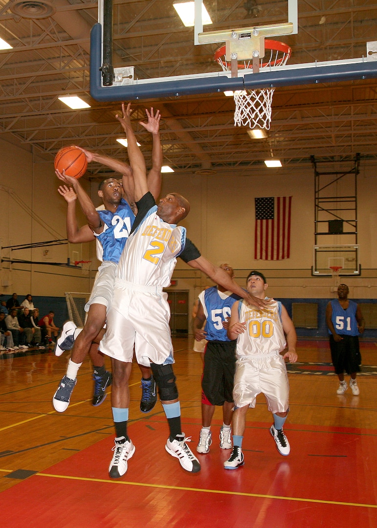 59th Medical Logistics Readiness Squadron point guard Alphius White drives the lane against two 802nd Security Forces Squadron Defenders March 16 at the Chaparral Fitness Center during the intramural championship. (U.S. Air Force photo/Robbin Cresswell)  