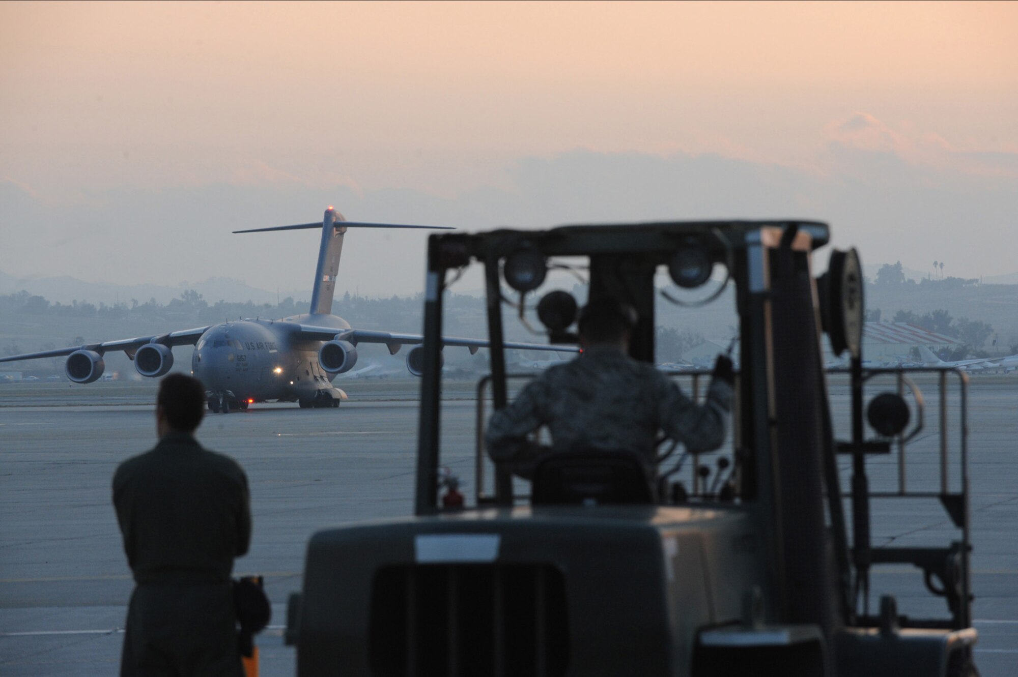 Airmen from the 452nd Air Mobility Wing's aerial port support flight watch as a C-17 Globemaster III from Travis Air Force Base, Calif., arrives at March Air Resere Base, Calif. The C-17 was loaded with 72 members of an urban search and rescue team and equipment bound for Port-au-Prince, Haiti, to assist with the earthquake relief effort. (Master Sgt. Roy Santana)