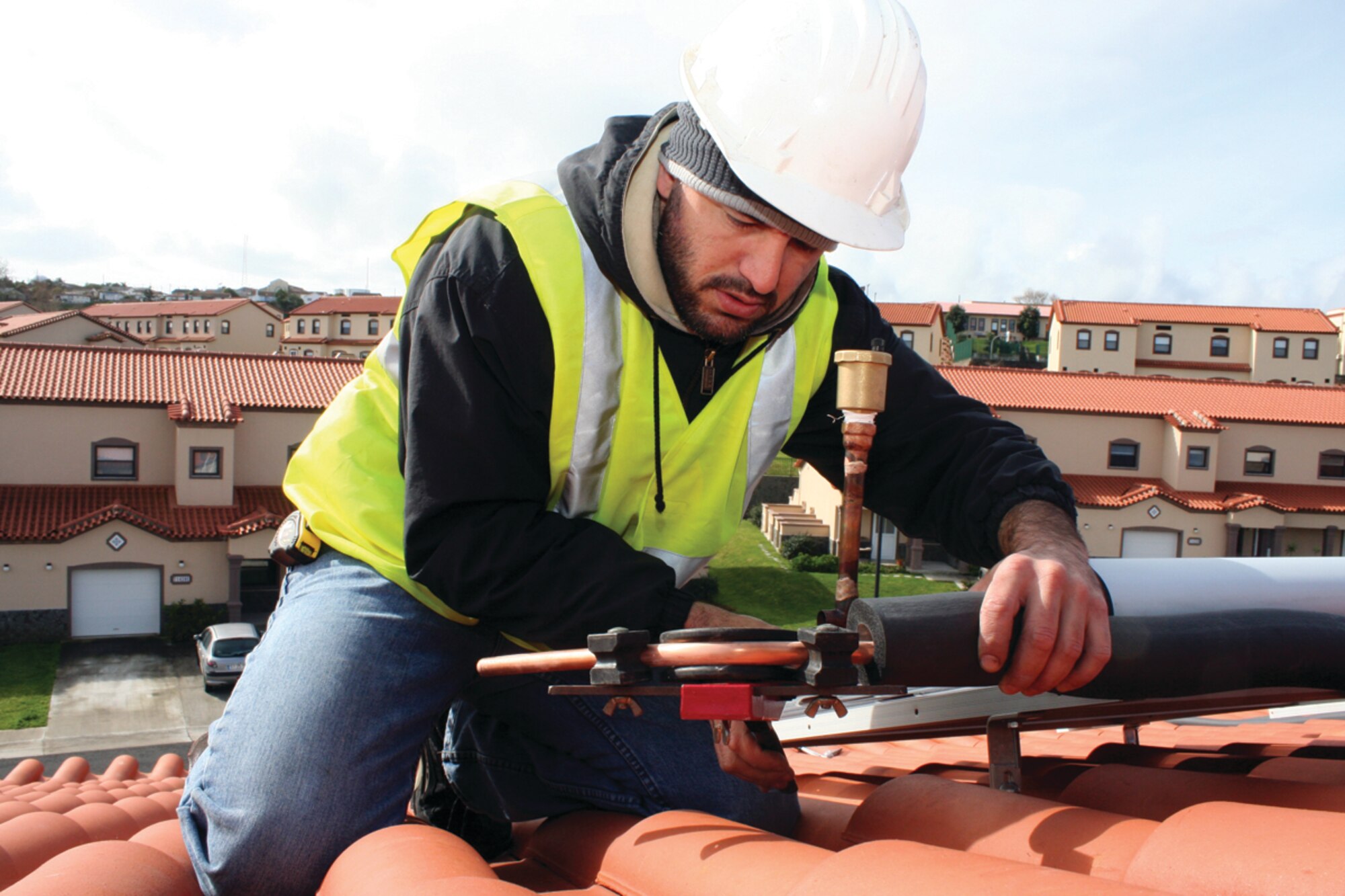 Emmanuel Borges, a local contractor with the 65th Civil Engineer Squadron, installs two solar panels in a military housing facility here Feb. 22.  This test installation is part of the Air Force’s renewable energy initiatives, which requires bases to obtain 30 percent of their hot water from solar heating.  (U.S. Air Force photo/Staff Sgt. Olufemi Owolabi)