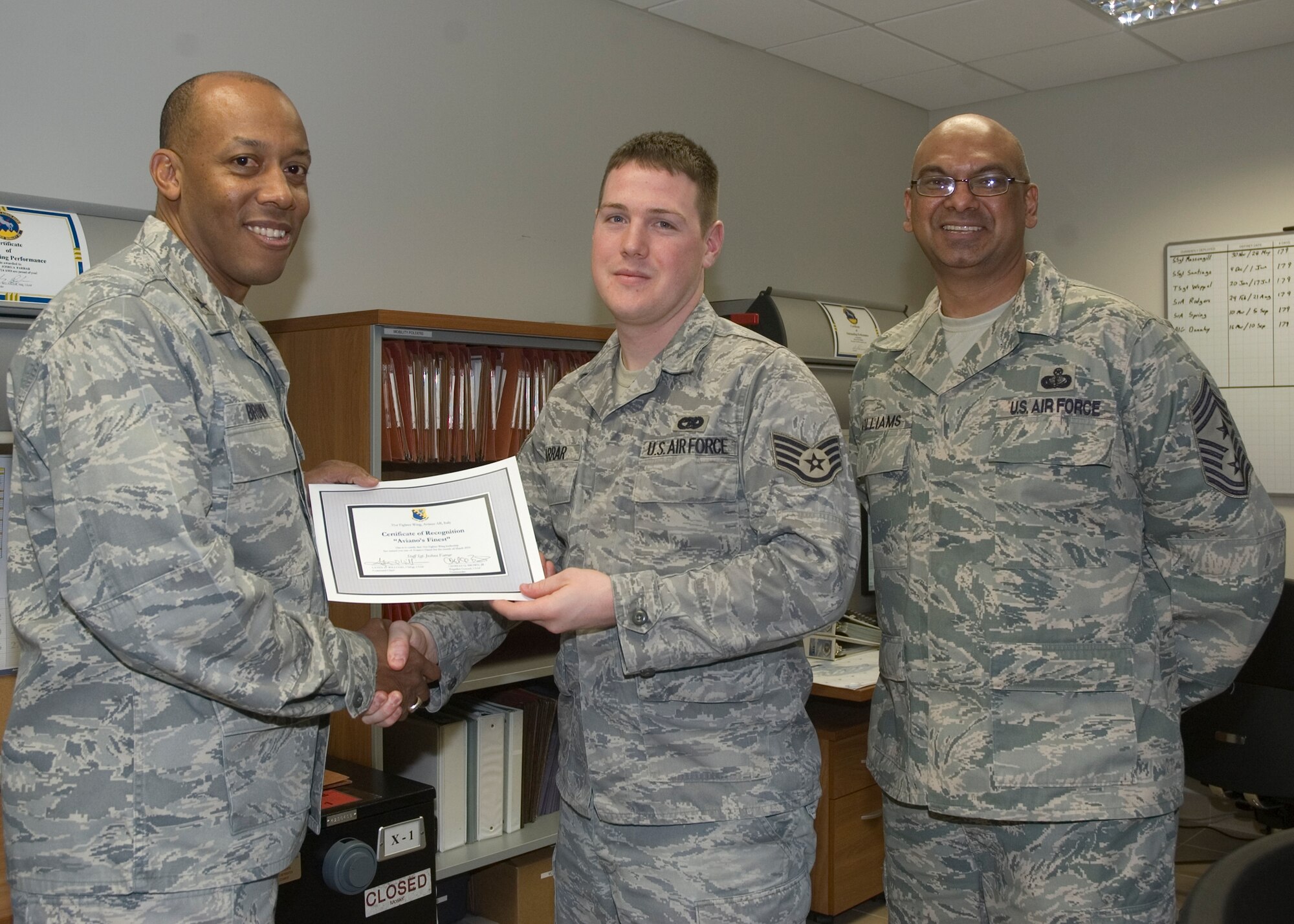 Brig. Gen. C.Q. Brown Jr., 31st Fighter Wing commander, congratulates Staff Sgt. Joshua Farrar, 724th Air Mobility Squadron unit deployment manager, on his selection as one of Aviano's Finest as Chief Master Sgt. Laten Williams, 31st FW command chief, looks on. (U.S. Air Force photo/ Staff Sgt. MercedesKimble Crossland) 

