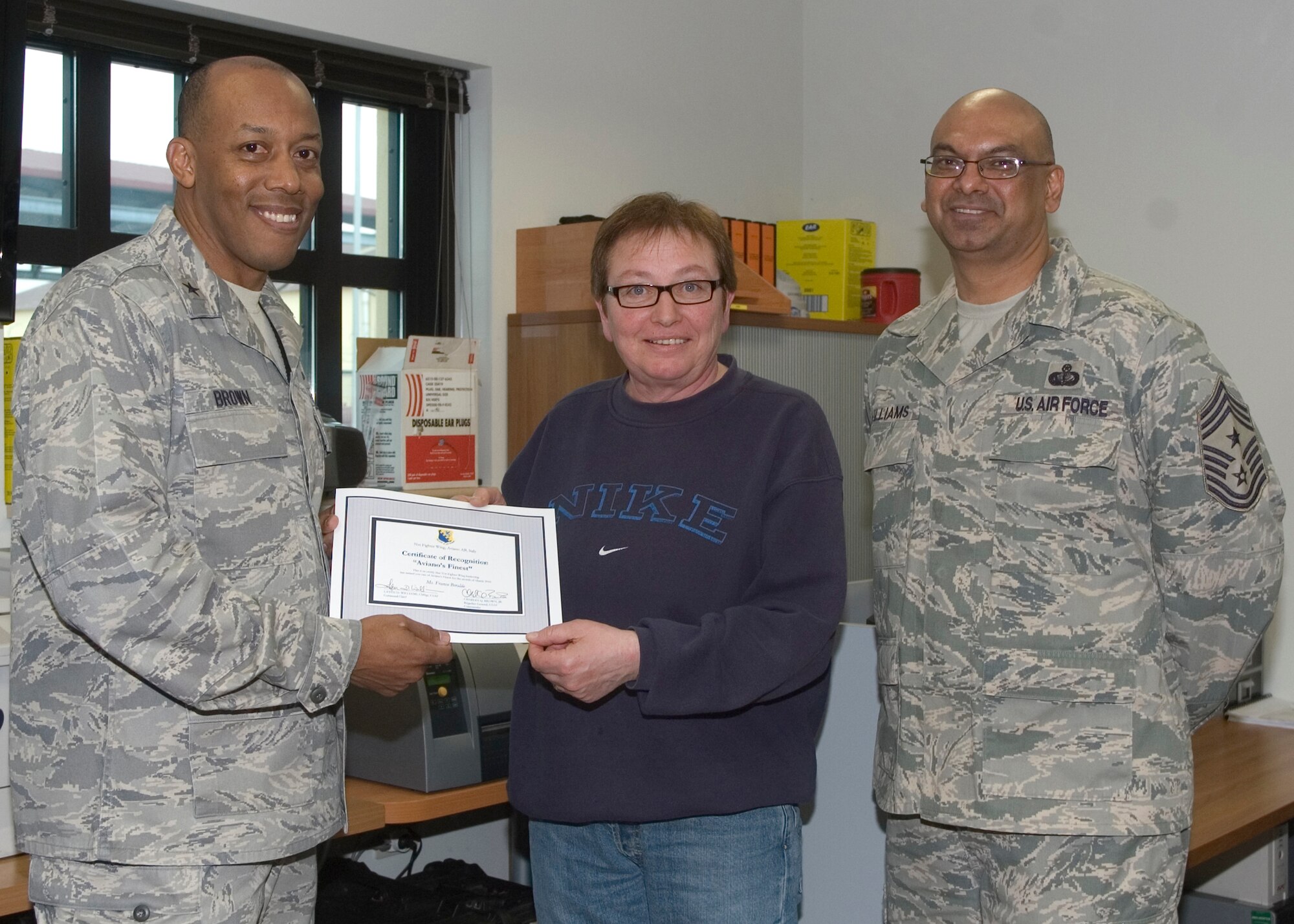 Brig. Gen. C.Q. Brown Jr., 31st Fighter Wing commander, congratulates Franca Beraldo, 724th Air Mobility Squadron, on her selection as one of Aviano's Finest as Chief Master Sgt. Laten Williams, 31st FW command chief, looks on. (U.S. Air Force photo/ Staff Sgt. MercedesKimble Crossland) 
