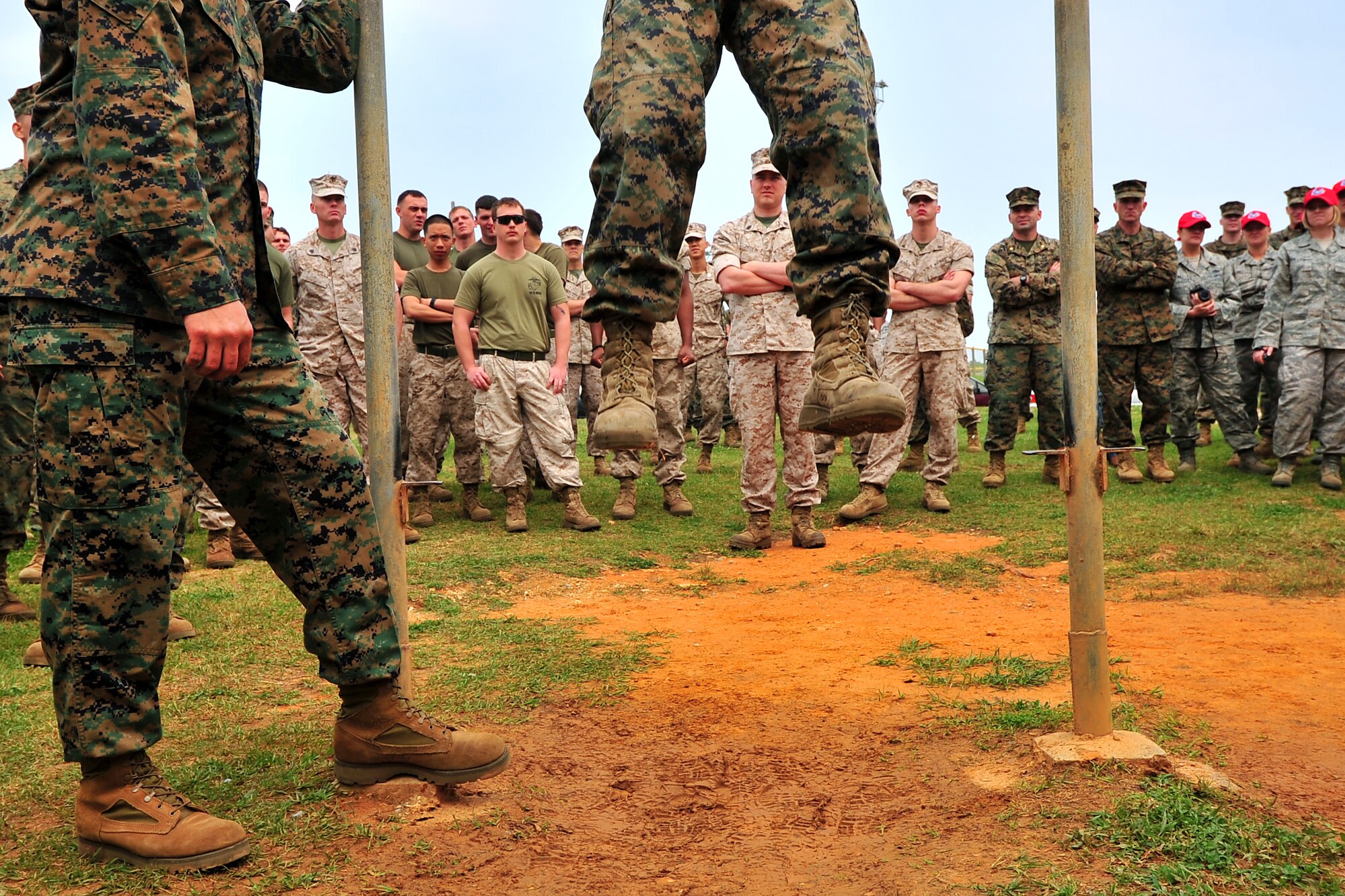 A marine strains for one more pullup as fellow servicemembers and engineers look on. 