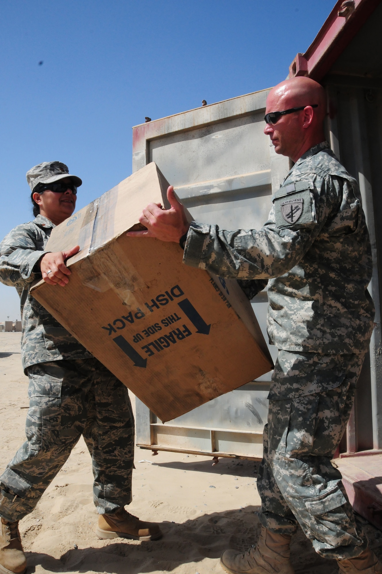 U.S. Air Force Maj. Carla Lugo and U.S. Army Sgt. Dominic Hauser, both of the 1st Theater Sustainment Command Civil Military Operations Center, load boxes of donated supplies into a 20-foot container to be taken downrange as part of a humanitarian aide shipment. (U.S. Air Force photo by Staff Sgt. Lakisha A. Croley)