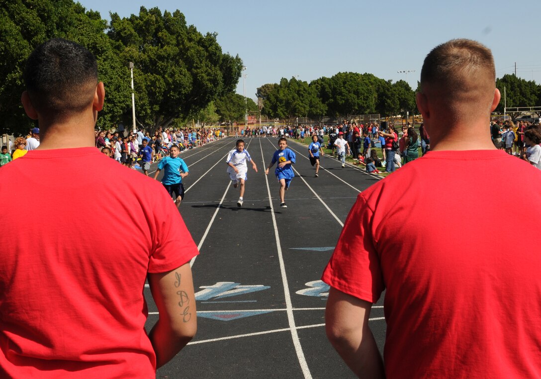 Lance Cpl. Joseph Sica, left, and Lance Cpl. Josh Beck, Combat Logistics Company 16 utilities mechanics, stand at the end of the 100-meter dash waiting to give runners their placing during a district track meet at Carver Park in Yuma March 19, 2010. Approximately 20 Yuma-based Marines volunteered their time to help set up the meet, which approximately 400 4th through 6th grade students from 18 schools participated in. “Helping kids is awesome,” said Cpl. Alexandra Aponte, Marine Wing Support Squadron 371 logistics clerk. “It’s really nice to get out here and show the community what Marines can do.”