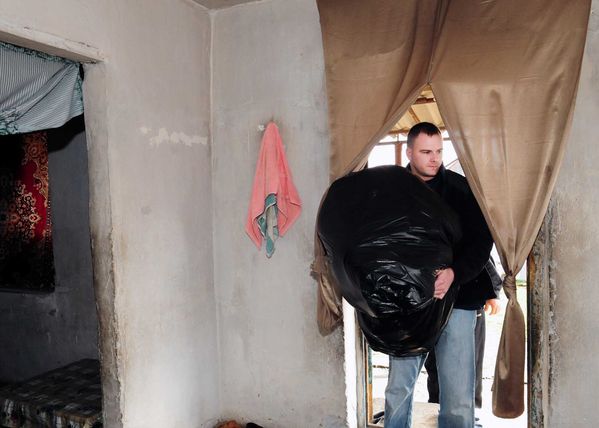 Air National Guard Tech. Sgt. Jake Mayo, 376th ELRS vehicle maintenance NCO in charge deployed from Birmingham, Ala., brings humanitarian assistance items collected from stateside bases and friends into the home of a family in Manas Village, Kyrgyzstan, March 18, 2010. (U.S. Air Force photo/Staff Sgt. Carolyn Viss/released)