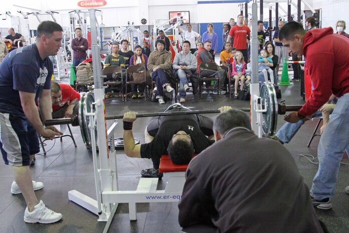 A crowd of people look on as a competitor struggles during the 2010 Open Bench Press Competition at the IronWorks Gym here March 20. Sixteen local Japanese and American athletes competed in the competition which tested their strength and endurance.