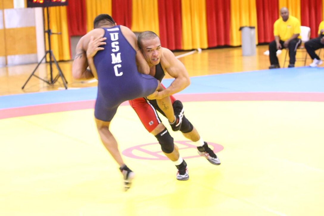 Staff Sgt. Matthew Ortiz, 4th and 6th place state medalist in high school and 69 kilogram wrestler on the All Marine Wrestling Team, receives a rough takedown from Spc. Mark Bradley with the All Army Wrestling Team, during their match in the Armed Forces Wrestling Championships.