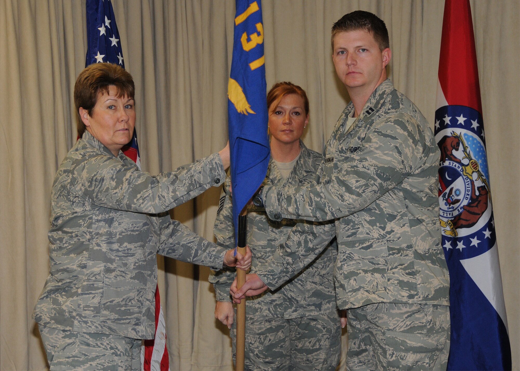 Capt. Joshua Hoormann accepts the 131st Communications Flight, guidon from Col. Terri Chaney, 131st Mission Support Group commander, during a change of command ceremony held at the Base Community Center, Lambert ANGB, March 21.  (U.S. Air Force photo by Master Sgt. Mary-Dale Amison  RELEASED)