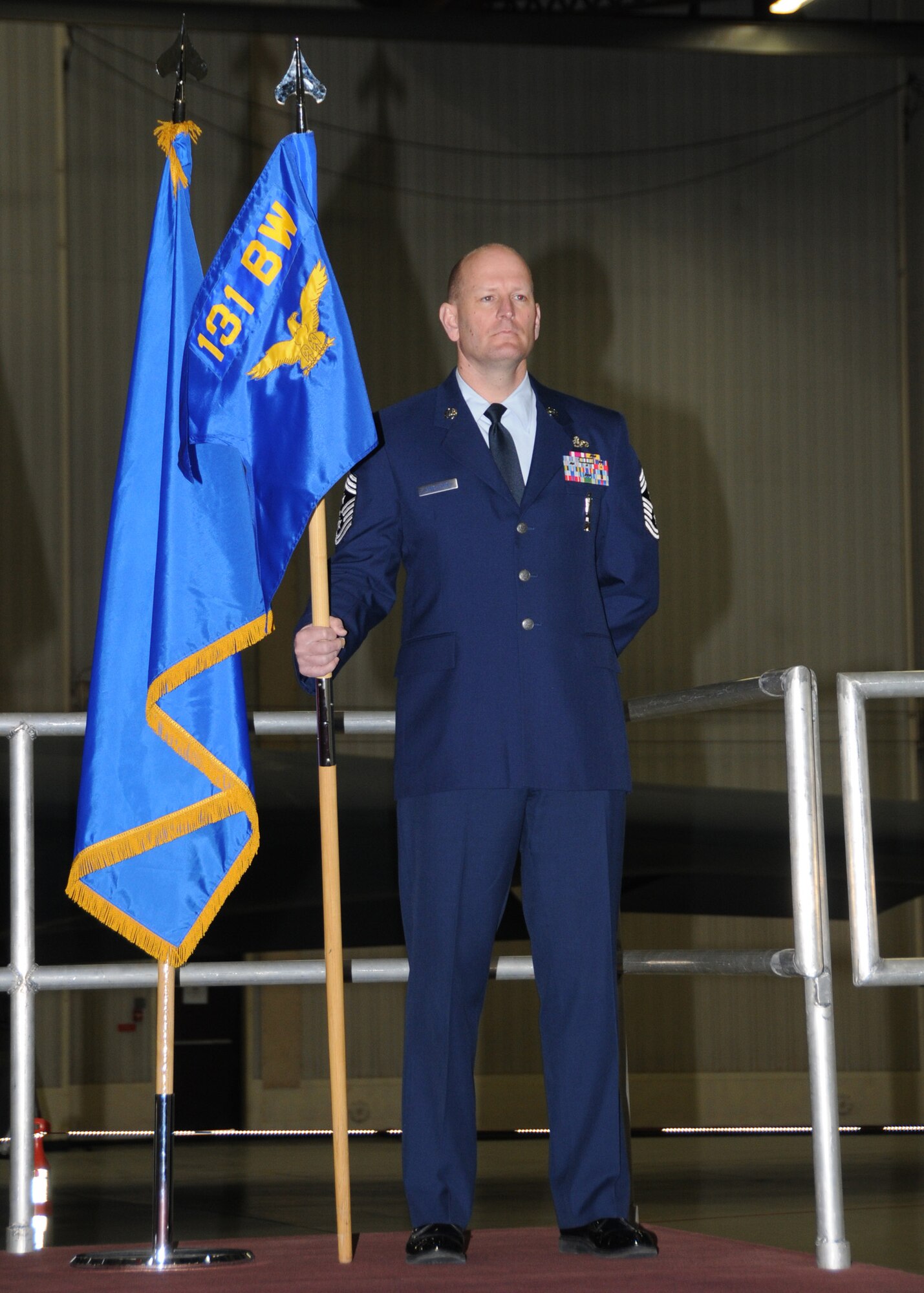 131st Bomb Wing Command Chief Master Sgt. Richard Pingleton, stands ready to pass the guidon during Col. Gregory Champagne's assumption of command ceremony at Whiteman AFB, March 20.  (U.S. Air Force photo by Master Sgt. Mary-Dale Amison  RELEASED)