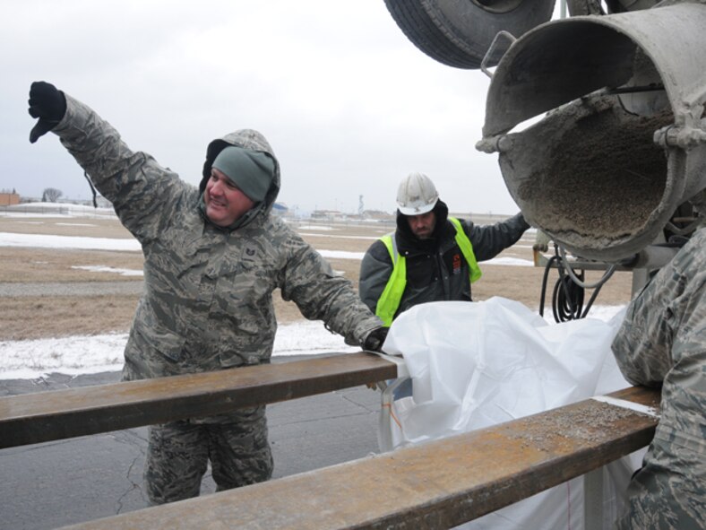 Tech Sgt. Kevin Reinhardt, of the 119th Logistics Readiness Squadron, signals a forklift driver as he completes filling a one-ton sandbag with sand from a cement truck March 19, at the North Dakota Air National Guard, Fargo, N.D., so the sandbags can be used in flood fighting operations.  The large sandbags are being readied for UH-60 helicopter sling-load operations, should they be necessary in emergency battling rising flood waters anywhere in eastern North Dakota.

