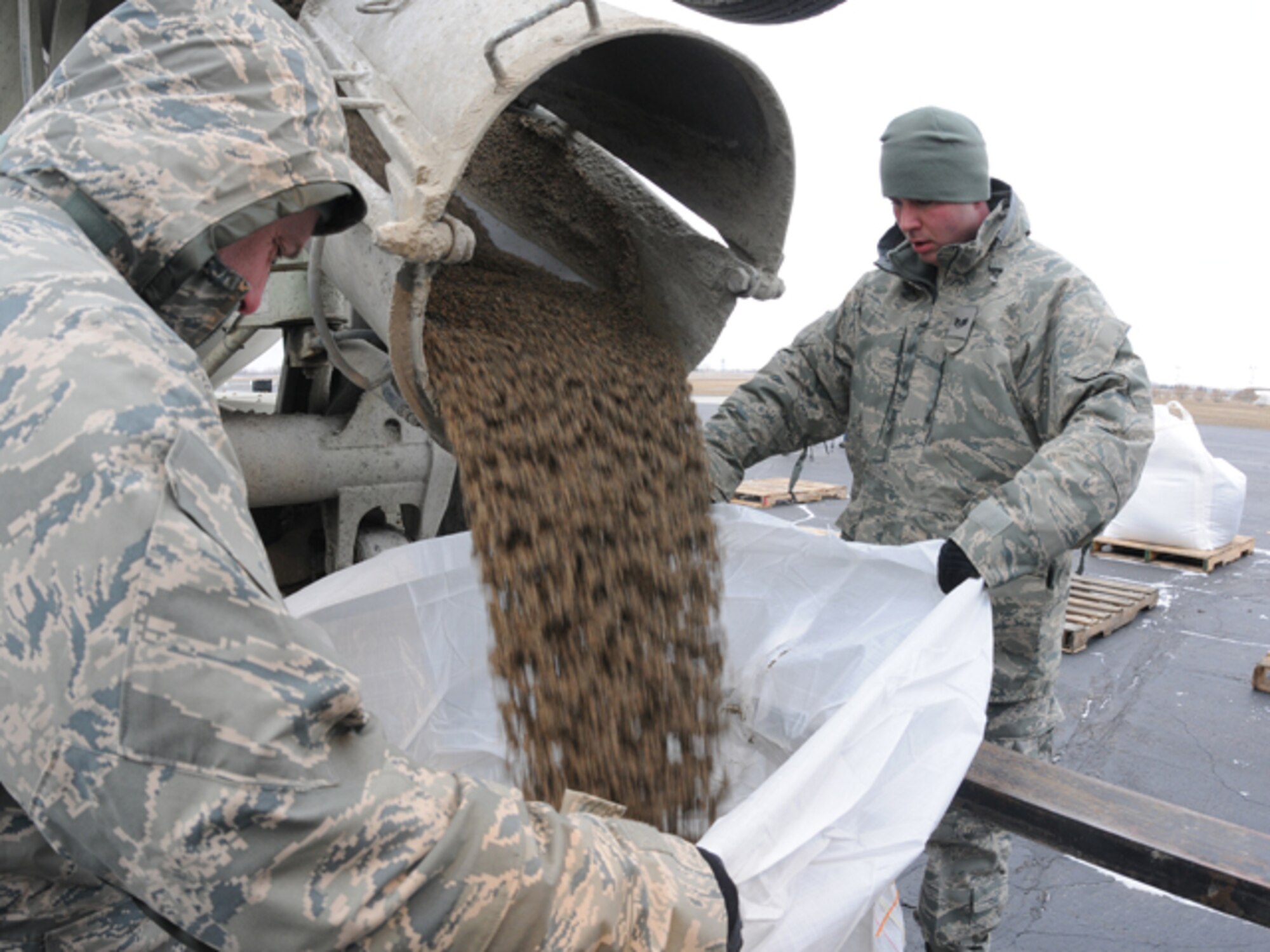 Tech Sgt. Kevin Reinhardt, left, and Staff Sgt. Anthony Salquist, both of the 119th Logistics Readiness Squadron, fill one-ton sandbags with sand from a cement truck, in preparation for use in flood fighting operations March 19 at the North Dakota Air National Guard, Fargo, N.D.  The large sandbags are being readied for UH-60 helicopter sling-load operations, should they be necessary in emergency battling rising flood waters anywhere in eastern North Dakota.